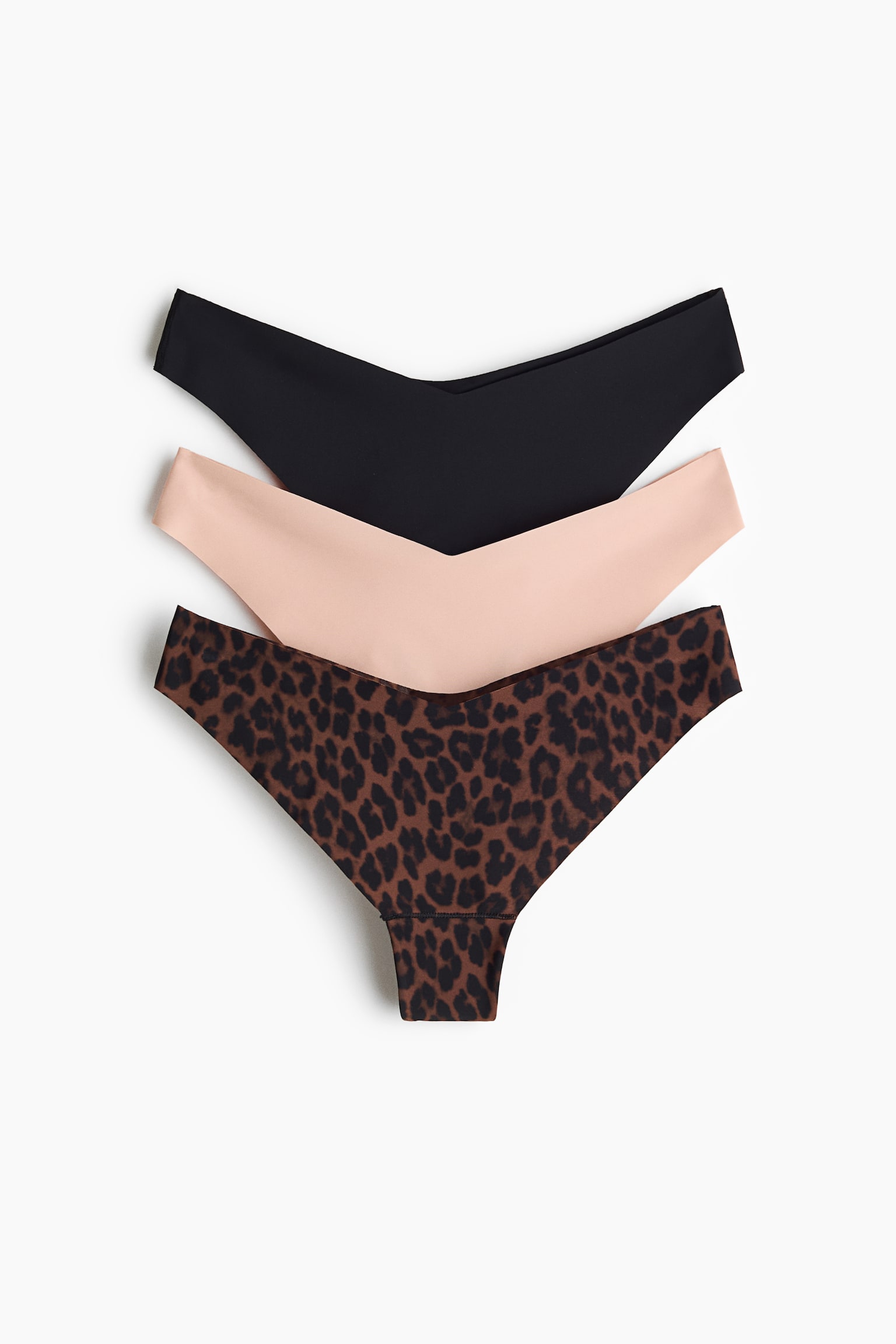 Drei Paar nahtlose Damen-Strings werden in einer vertikalen Stapelung von vorne präsentiert. Das Set umfasst oben ein einfarbig schwarzes Paar, in der Mitte ein einfarbig hellpfirsichfarbenes Paar und unten ein braun gemustertes Paar im Leopardenprint, alle mit einem tief ausgeschnittenen, V-förmigen Bund gestaltet.