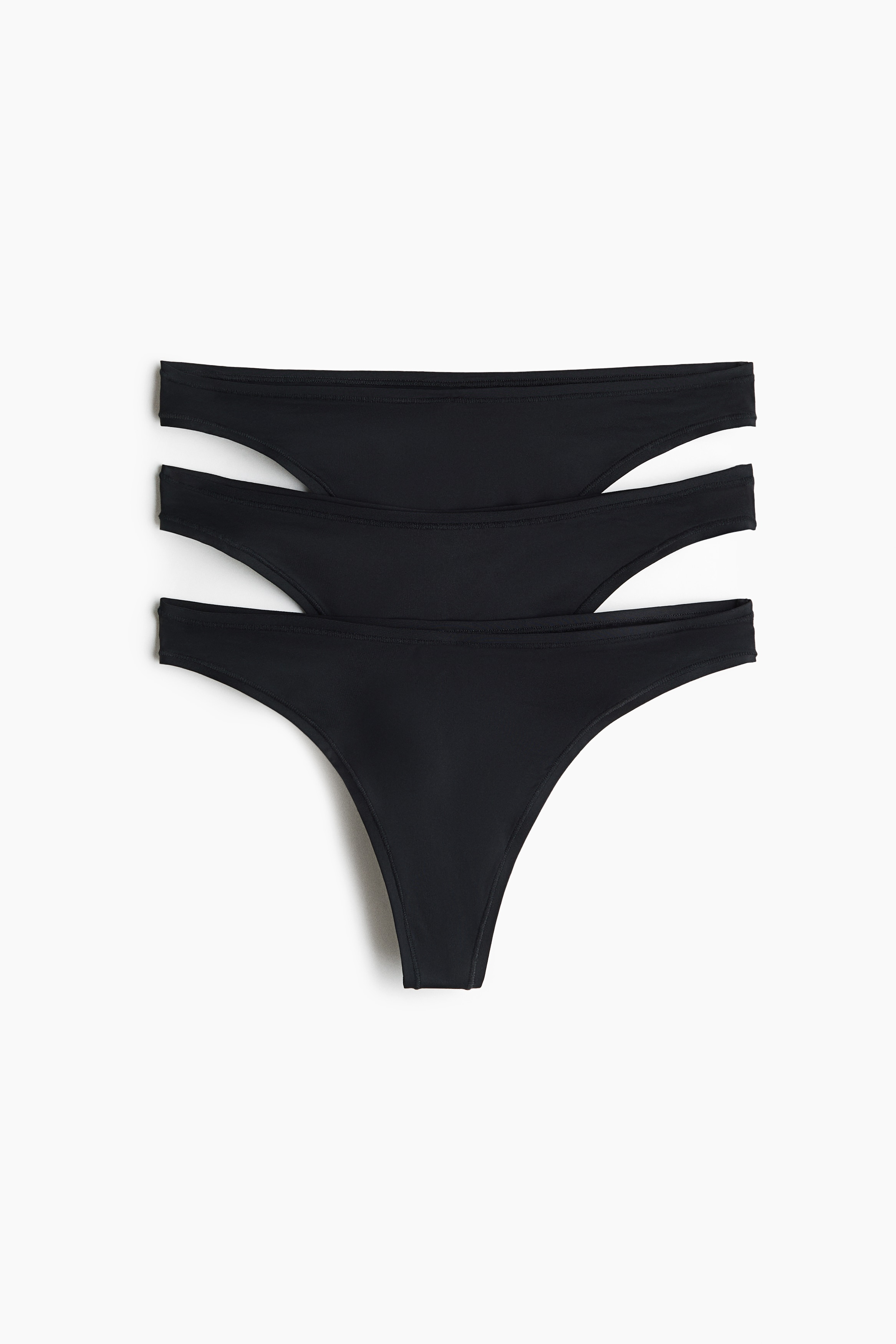 Un sujetador negro con aros, copas moldeadas y alas laterales de malla transparente se presenta con unas bragas tipo bikini negras a juego. Las bragas tienen un discreto detalle fruncido en las tiras de la cadera, con ambas piezas ligeramente orientadas hacia la derecha.