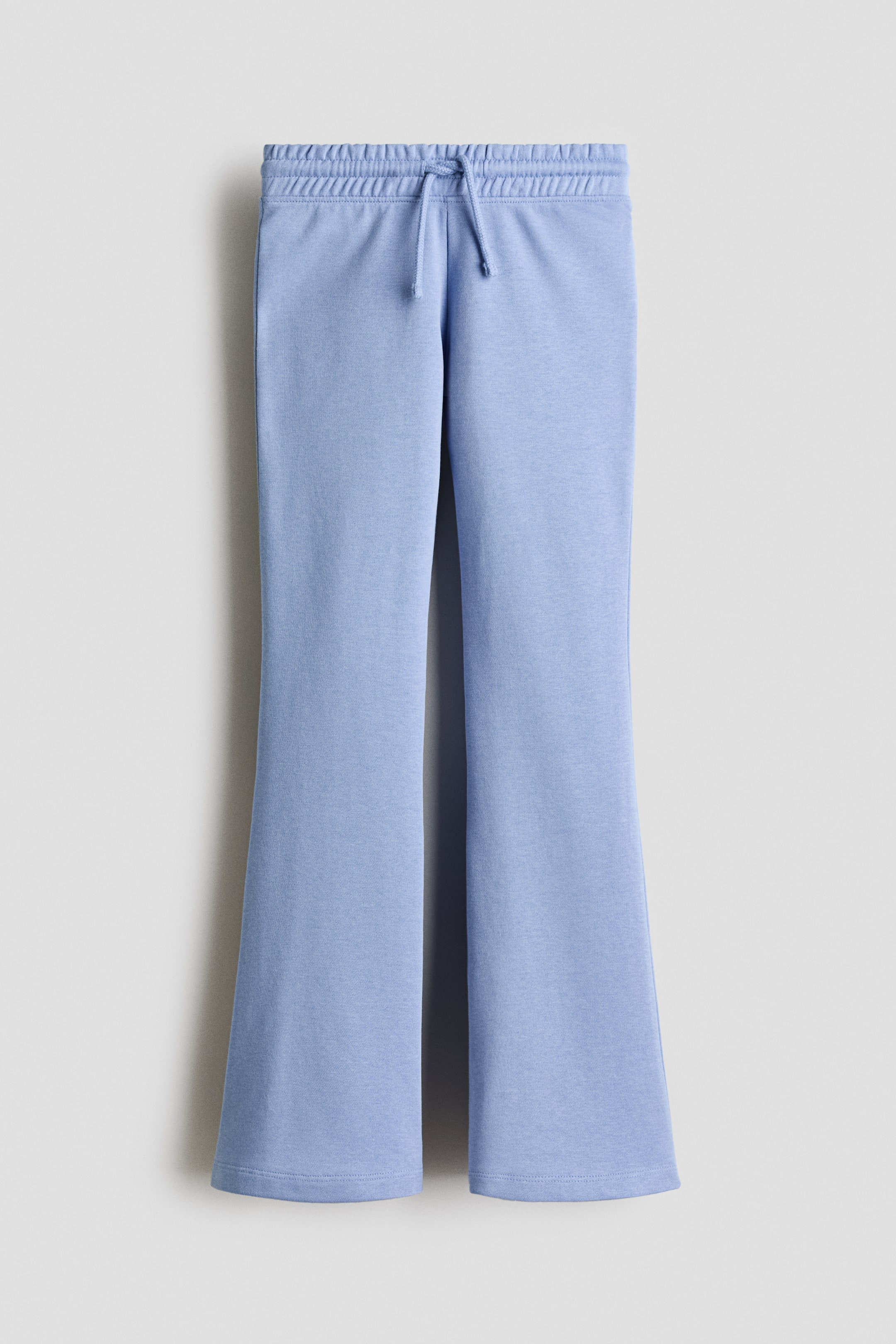 Agrandir l'image: Jogging bleu clair en tissu de sweat-shirt, avec taille élastiquée et cordon de serrage et jambes évasées, présenté de face.