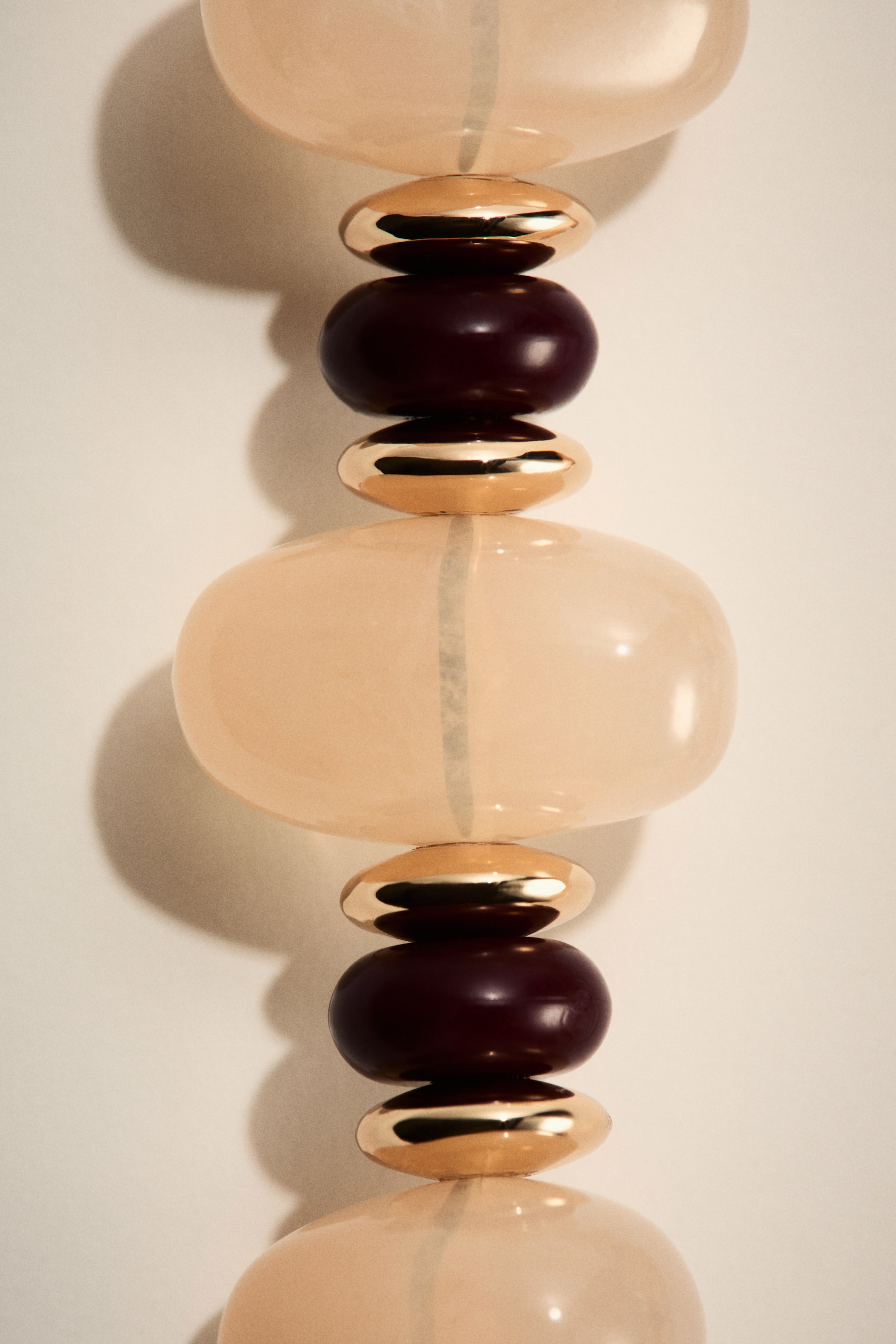 Преглед на по-голямо изображение: Въже колие с последователност от светли полупрозрачни удължени овални мъниста, тъмни непрозрачни заоблени мъниста и метални златисти плоски овални мъниста, всички нанизани вертикално.