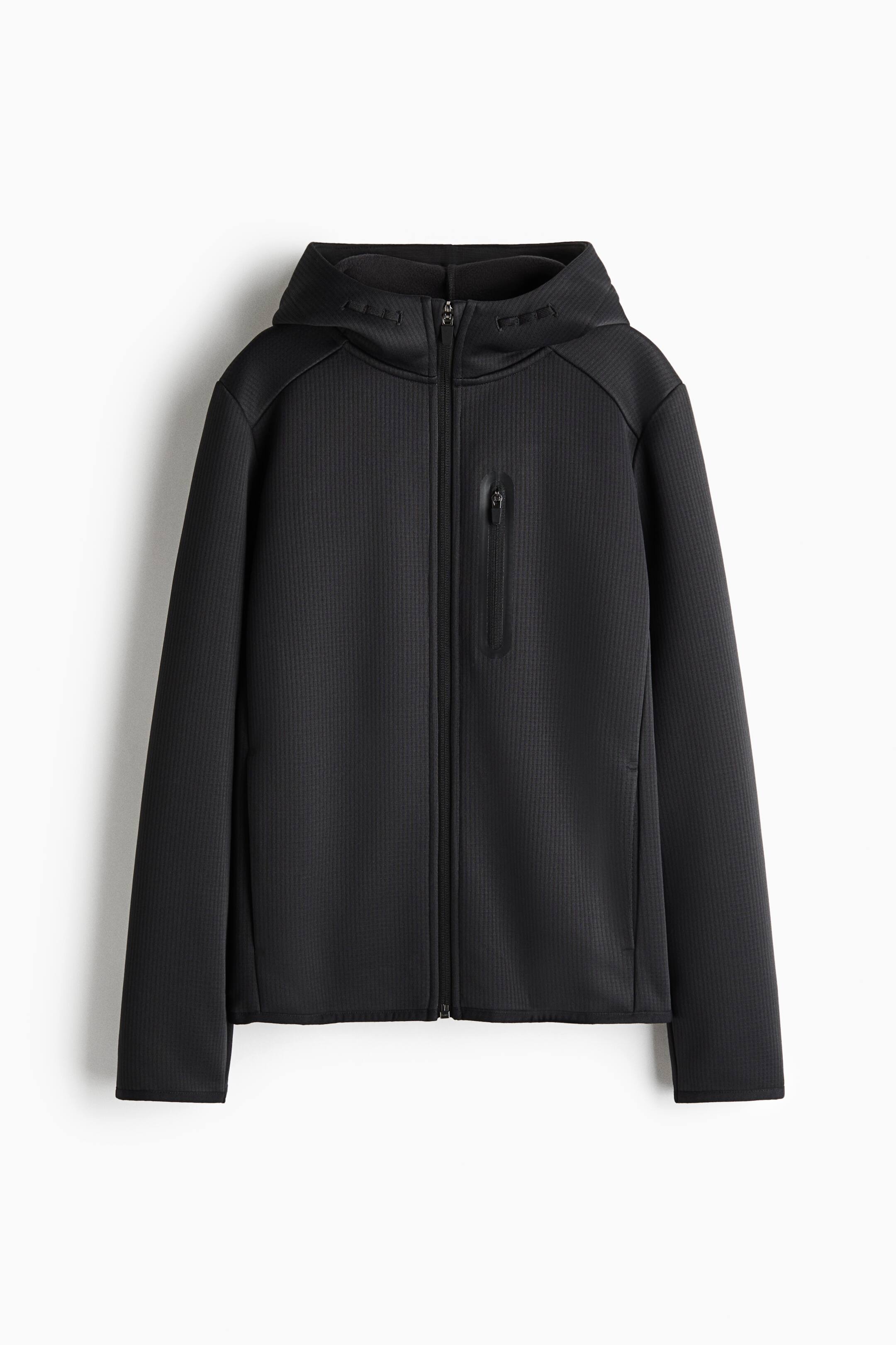 View larger image: A black, textured zip-up hoodie is shown facing forward, featuring a full-length centre zip and an attached hood. The jacket features a vertical zip chest pocket with a taped border on the left side and a fine, vertically ribbed fabric pattern throughout.