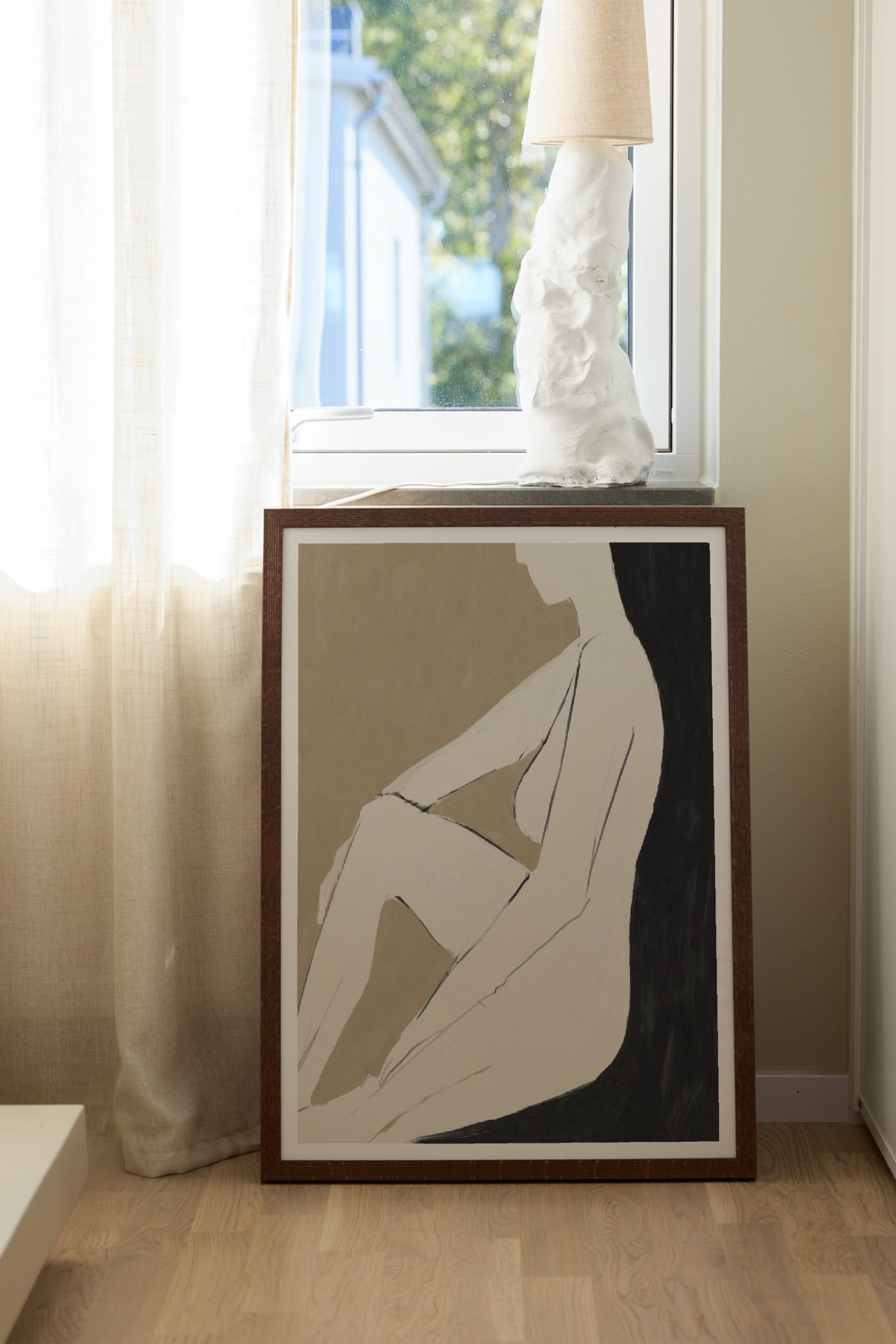 Se større billede: Et indrammet kunsttryk viser en minimalistisk, abstrakt illustration af en nøgen figur i profil, der sidder ned. Kunstværket fremhæver en lysebeige figur, aftegnet med mørke penselstrøg mod en delt baggrund i afdæmpet olivengråbrun og ensartet sort, alt sammen indrammet af en mørkebrun træramme.