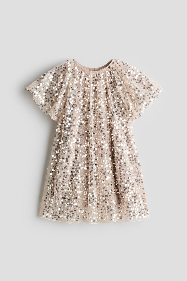 Une robe Ã  sequins est prÃ©sentÃ©e de face, avec un empiÃ¨cement en tulle beige clair recouvert de sequins argentÃ©s scintillants. La robe met en valeur un col rond avec dÃ©tails froncÃ©s, des manches courtes volantÃ©es et une silhouette Ã©vasÃ©e en ligne A. - 1