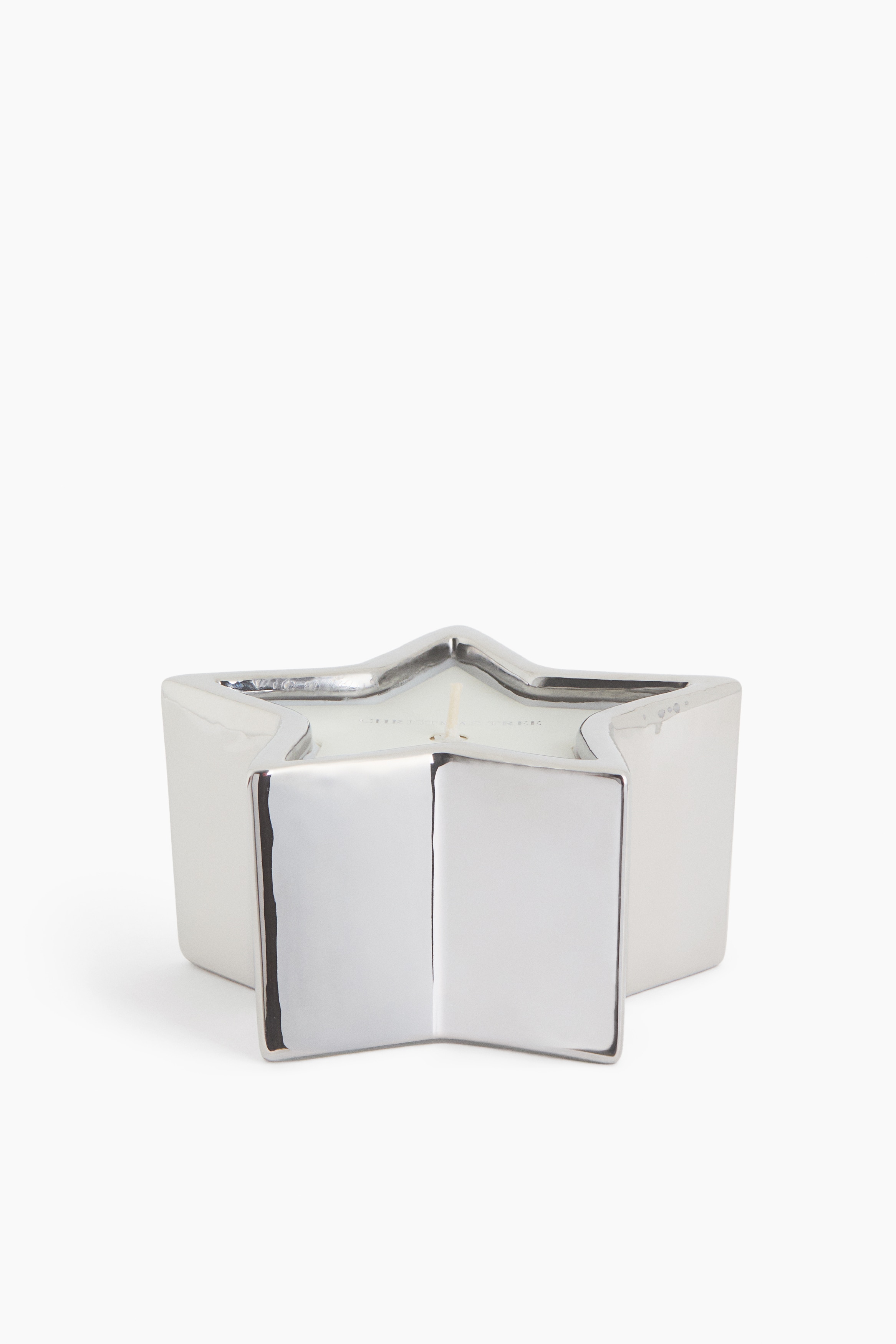 Une bougie en forme dâÃ©toile Ã  cinq pointes repose dans un porte-bougie en grÃ¨s Ã©maillÃ© argent brillant, vue en plongÃ©e. La cire blanche remplit le contenant en forme dâÃ©toile et prÃ©sente une seule mÃ¨che foncÃ©e au centre.