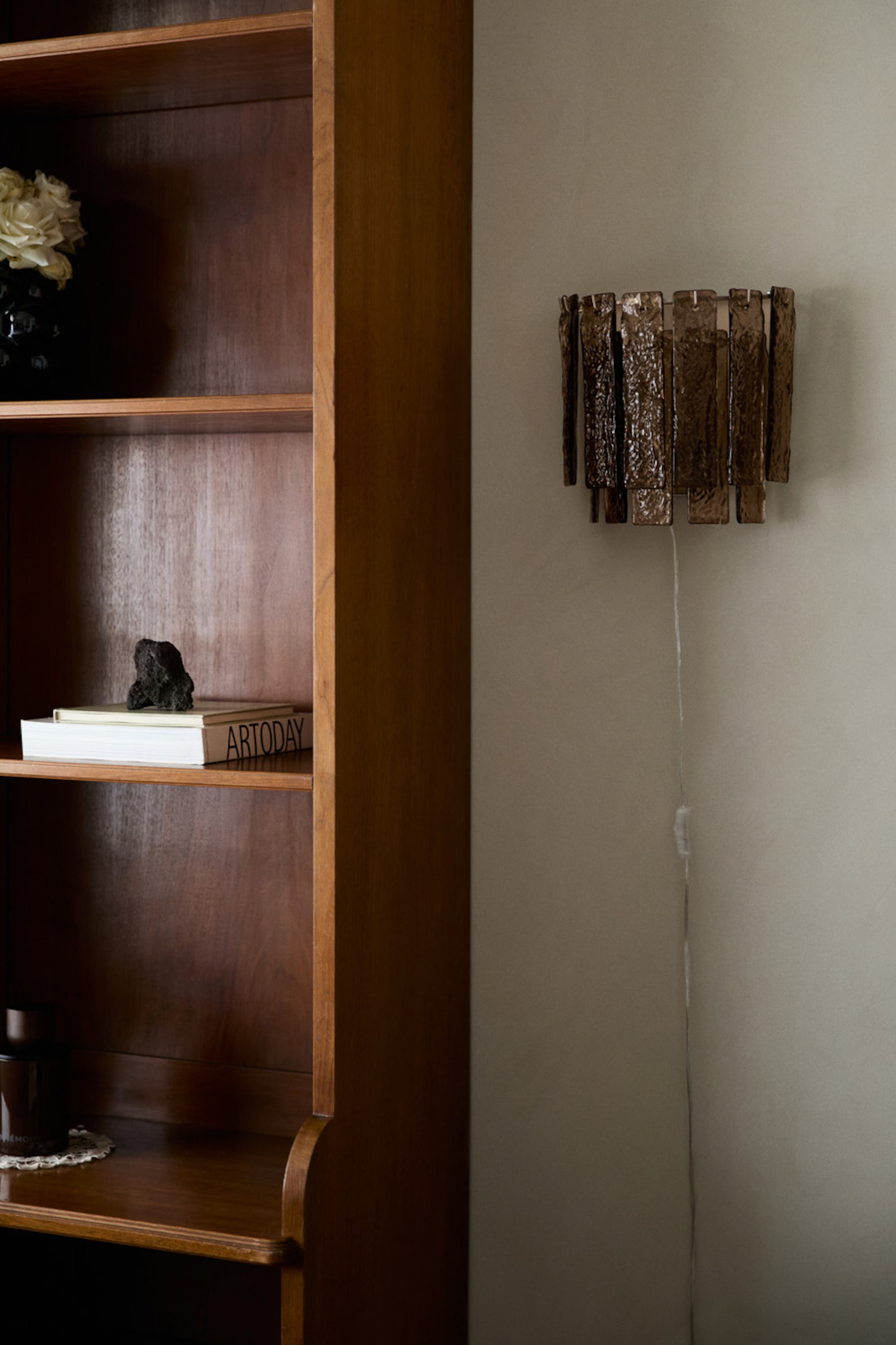 View larger image: A wall sconce featuring multiple textured, rectangular panels of smoky brown glass, arranged in a tiered design and mounted on a wall. A white power lead extends downwards from the bottom of the sconce.