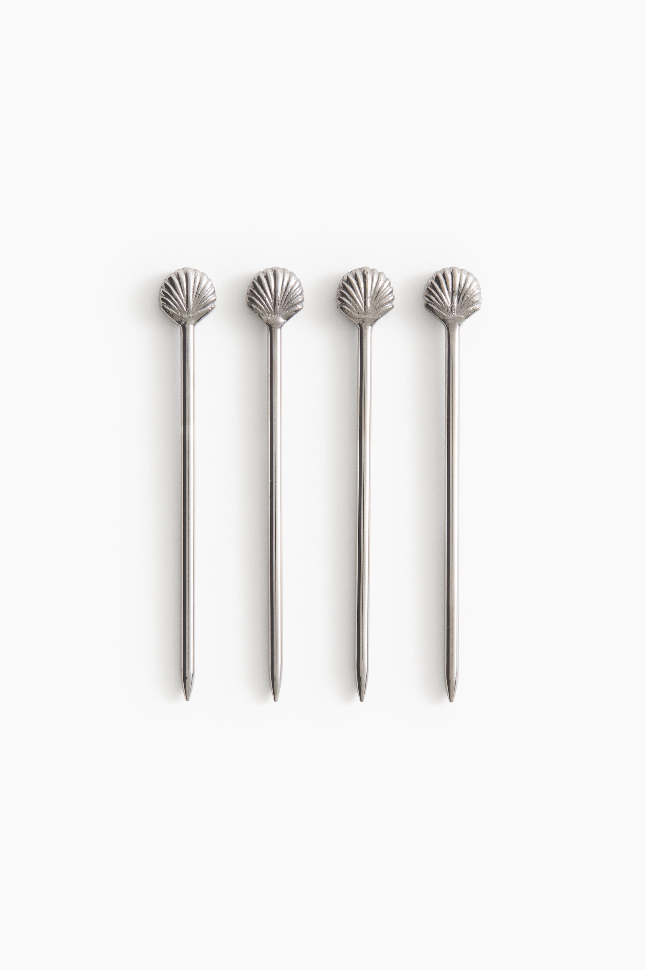 View larger image: A set of four silver cocktail picks is presented at the FRONT, each adorned with a decorative scallop shell top featuring radial ridges and a slender shaft tapering to a pointed end.
