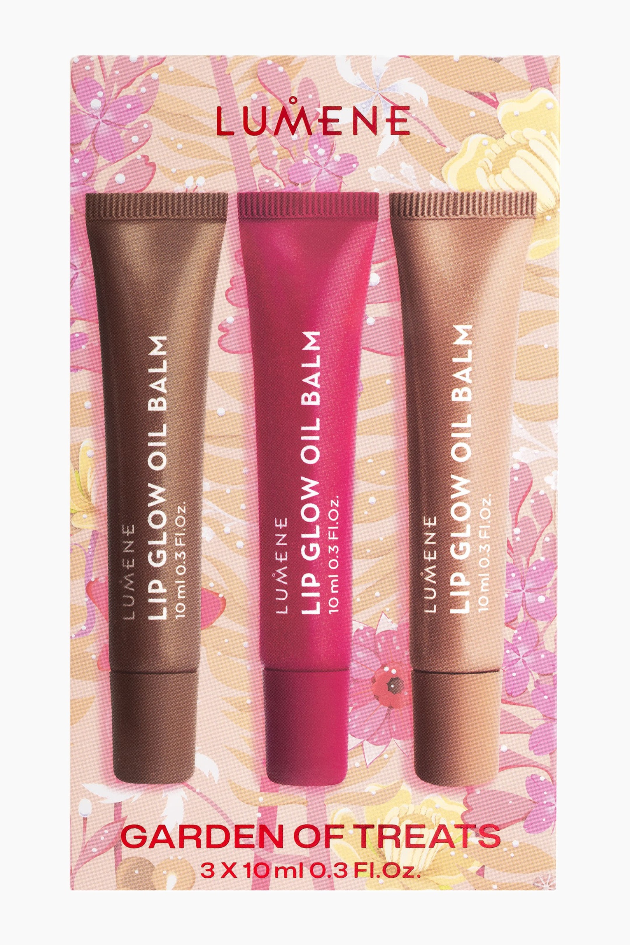 Visa större bild: Tre klämtuber med Lumene Lip Glow Oil Balm står sida vid sida i ett dekorativt blomsterförpackning märkt "Garden of Treats". Tuberna visar nyanserna mörkbrun, livfull bärrosa och ljus nude-brun, där varje tub har vertikal vit varumärkestext.