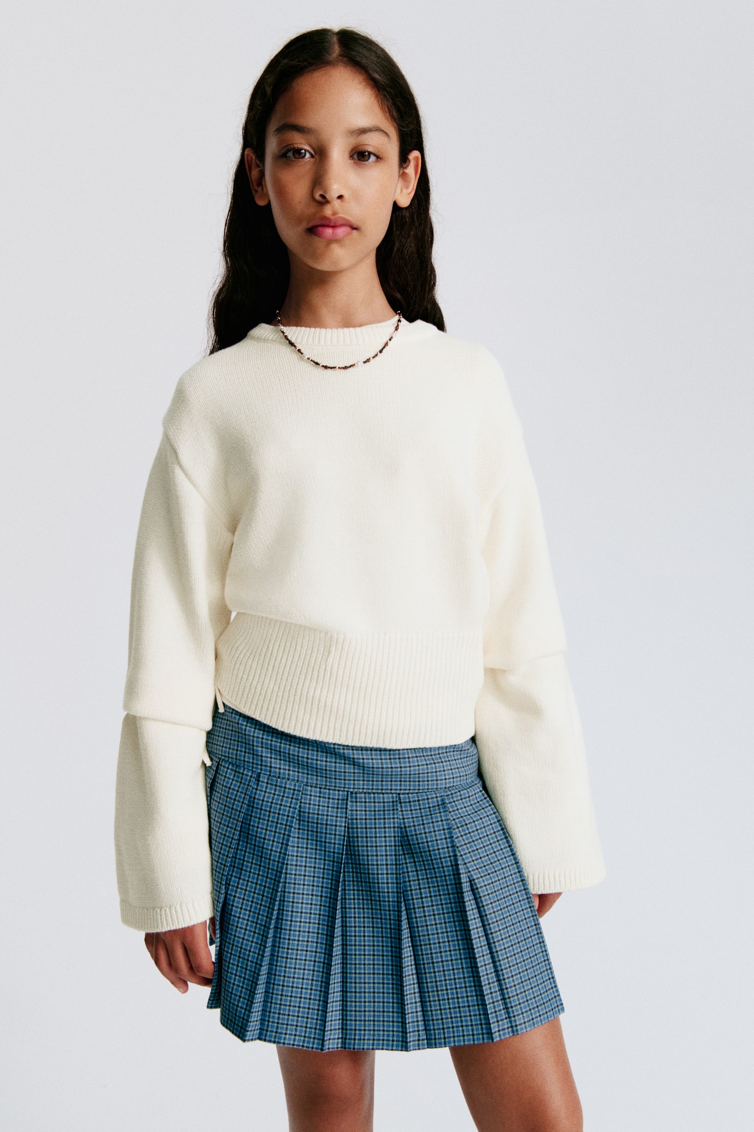A cream knitted jumper is shown front-facing, featuring a ribbed crew neck, wide long sleeves, and a cropped ribbed hem. - 1
