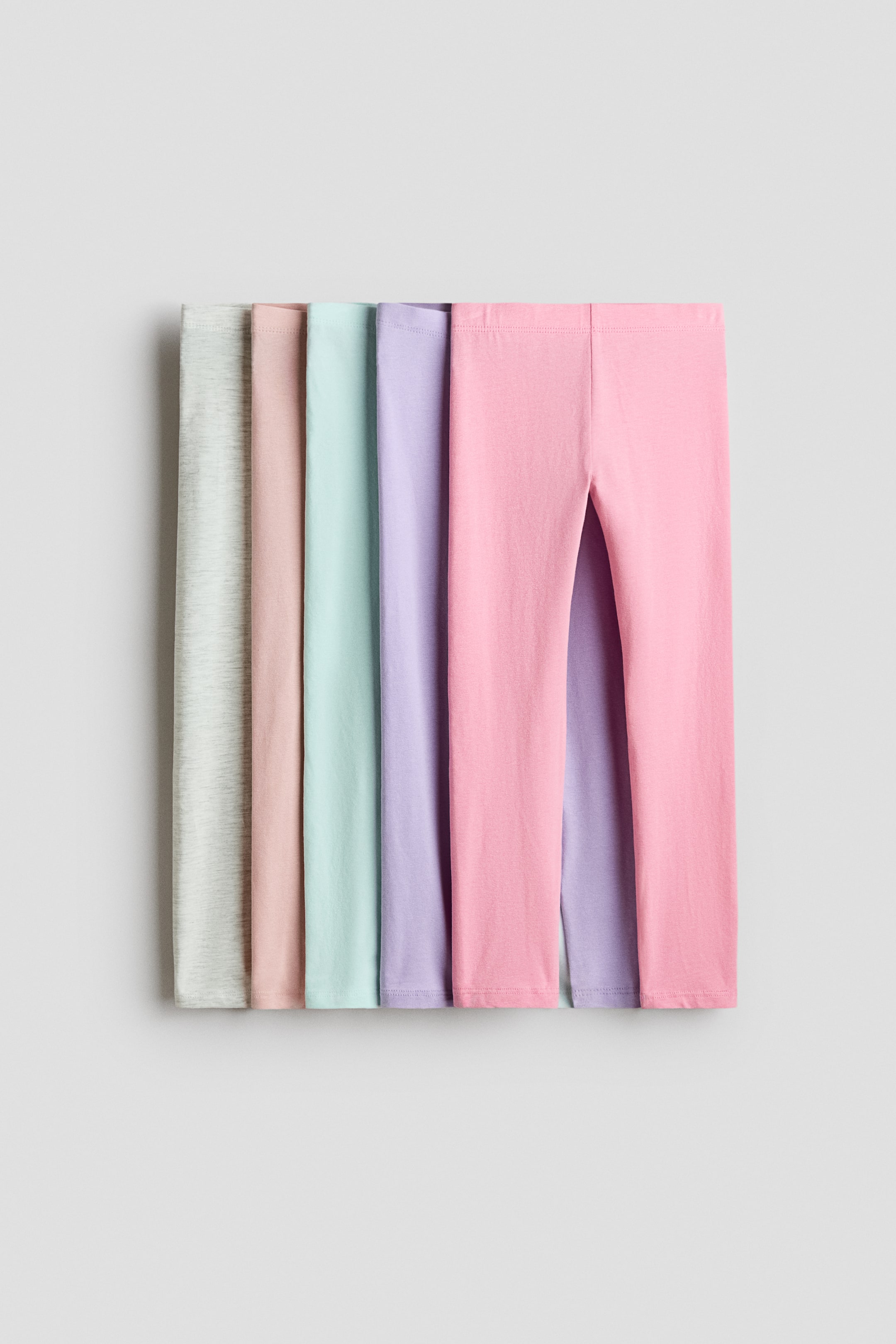 View larger image: Soft cotton jersey leggings with an elasticized waist are laid flat and arranged in a row in five different pastel colors. Each pair is shown from the front, highlighting the smooth fabric and simple design.