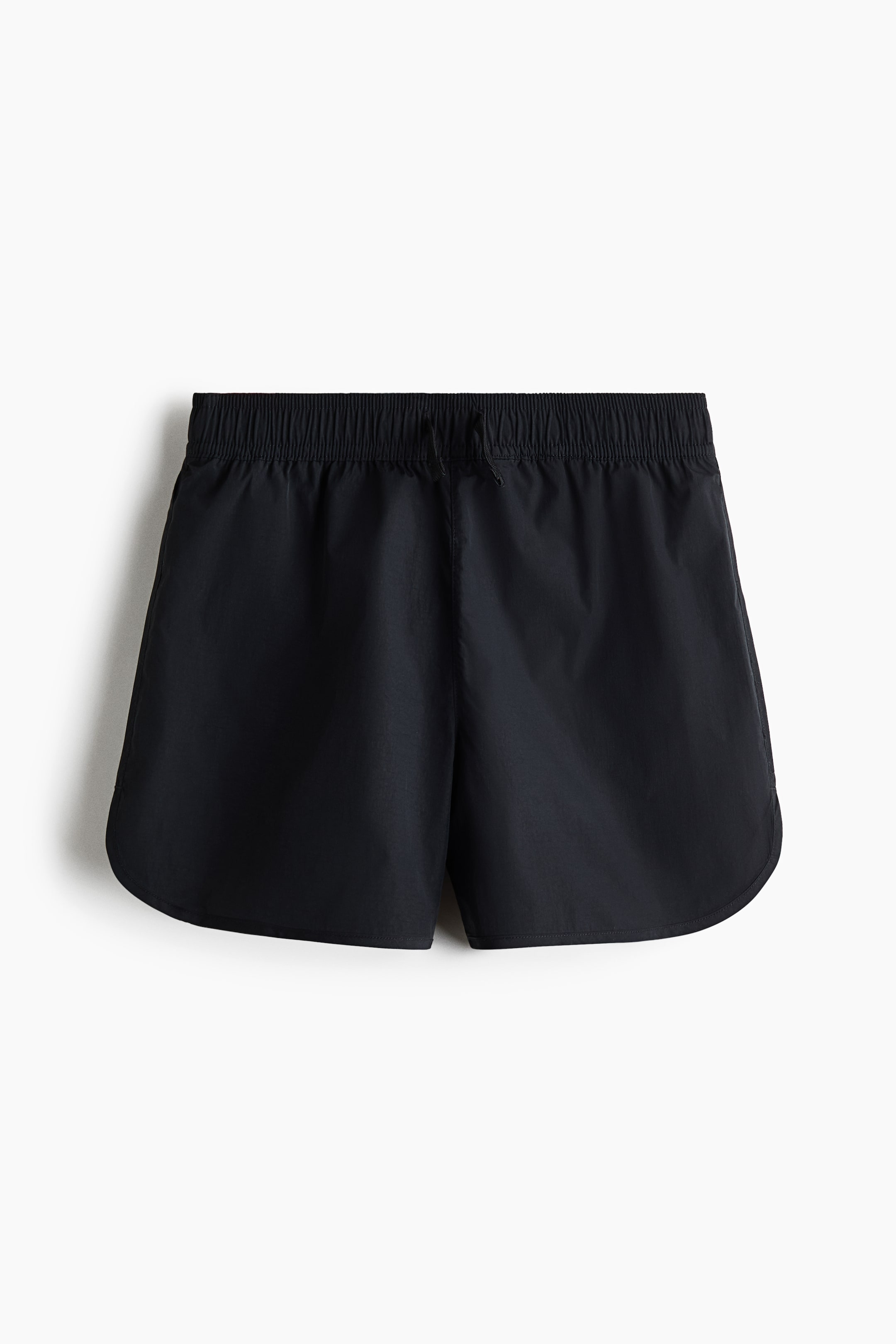 View larger image: Black shorts showcase an elastic waistband with a visible drawstring tie at the front. The shorts feature a lightweight fabric with a subtle texture and a curved hemline along the outer sides.