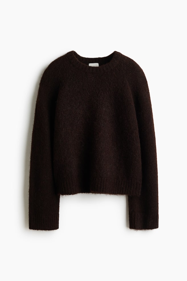 An oversized dark brown jumper in a soft, fuzzy knit is shown from the front, featuring a round, rib-trimmed neckline, long sleeves with ribbed cuffs, and a ribbed hem. - 1
