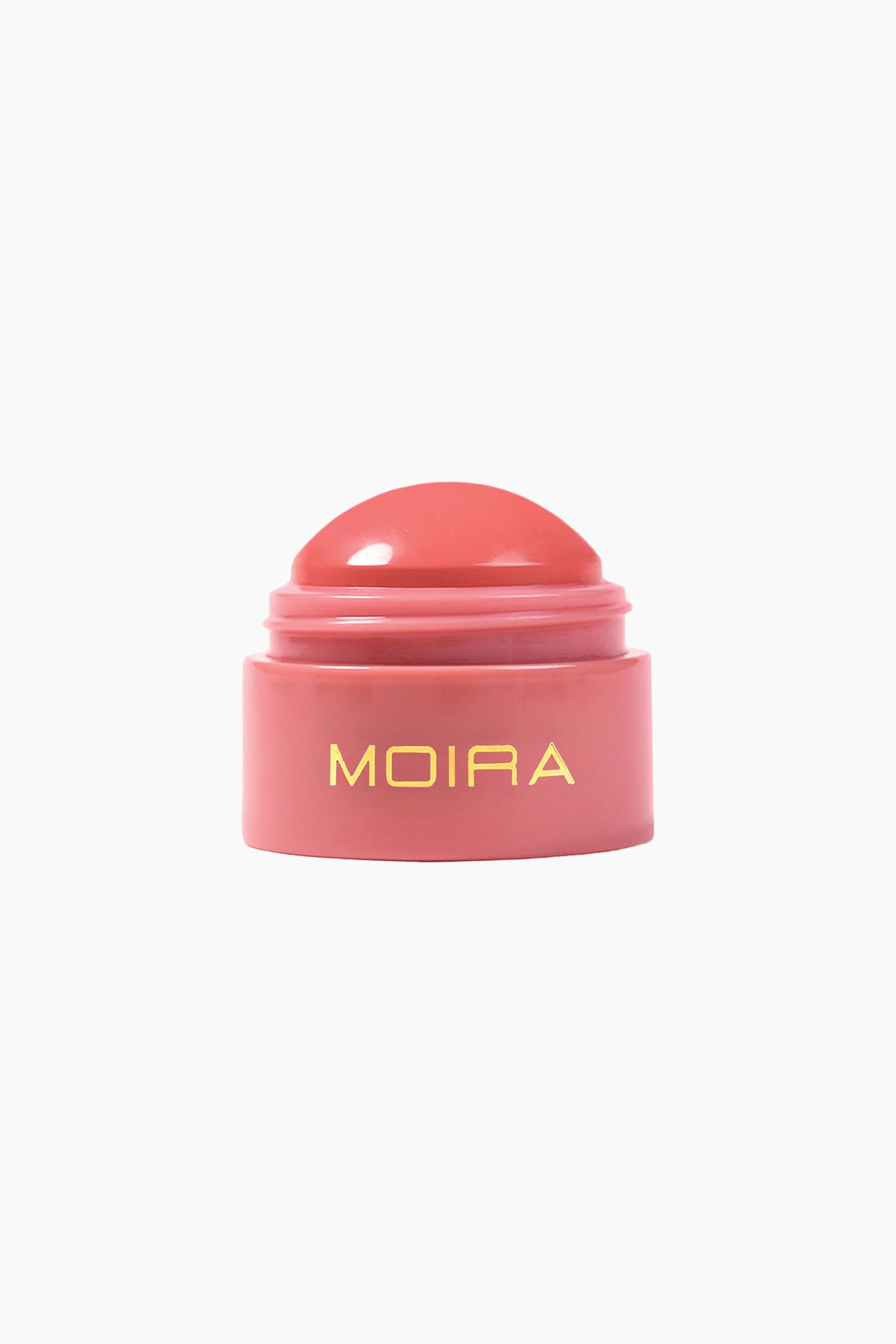 Visa större bild: En kupolformad rougebalm i korallrosa står upprätt och visar upp sin släta, rundade produktspets som sticker upp från en matchande cylindrisk bas. Framsidan av den rosa basen visar varumärkesnamnet "MOIRA" i guldbokstäver.