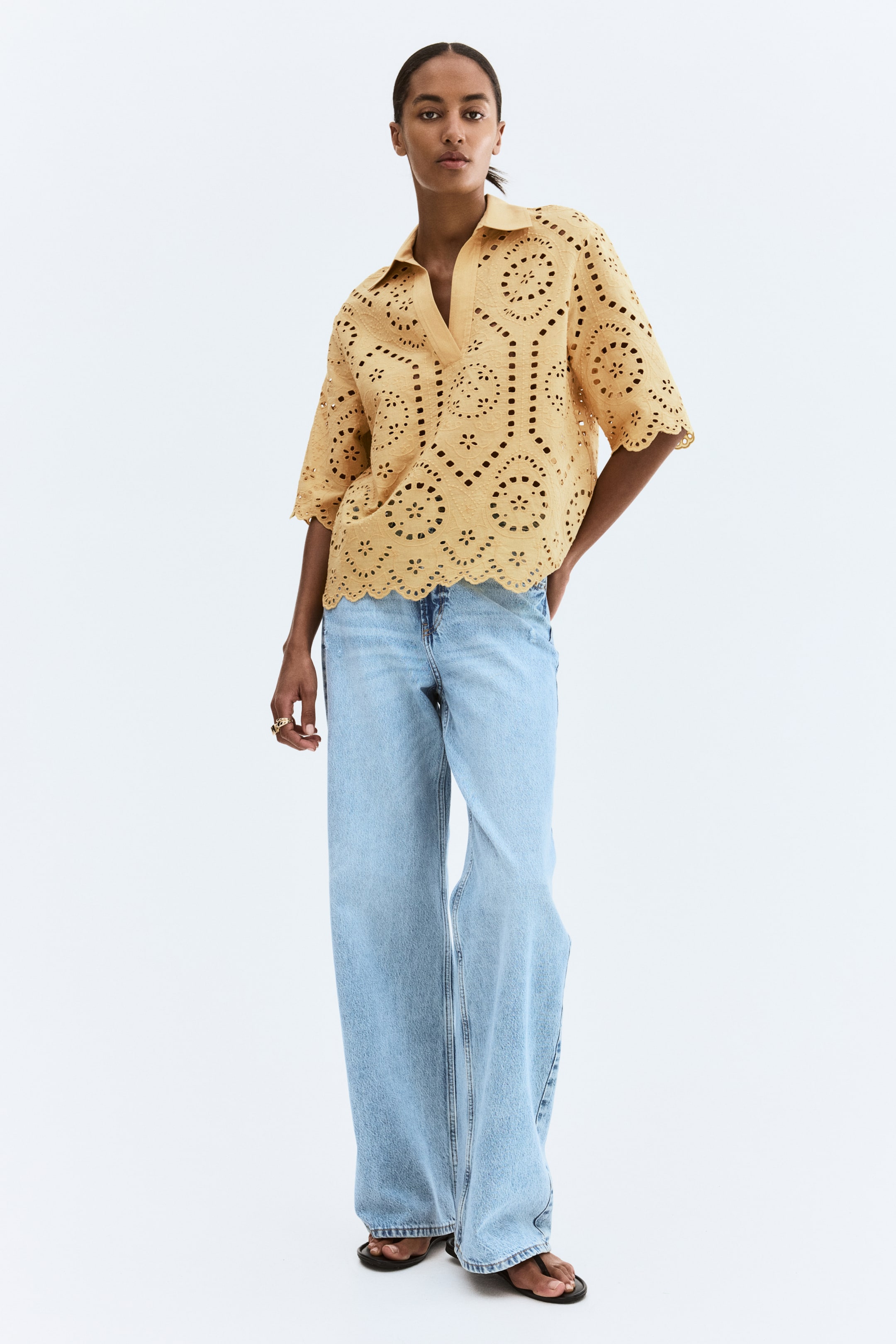 Xem ảnh lớn hơn: Áo màu vàng mù tạt nổi bật với thêu lỗ kim toàn bộ trong các họa tiết hoa và hình học. Thiết kế với cổ polo, đường xẻ cổ chữ V và các cạnh viền hình vỏ sò trên tay áo ngắn và gấu áo.