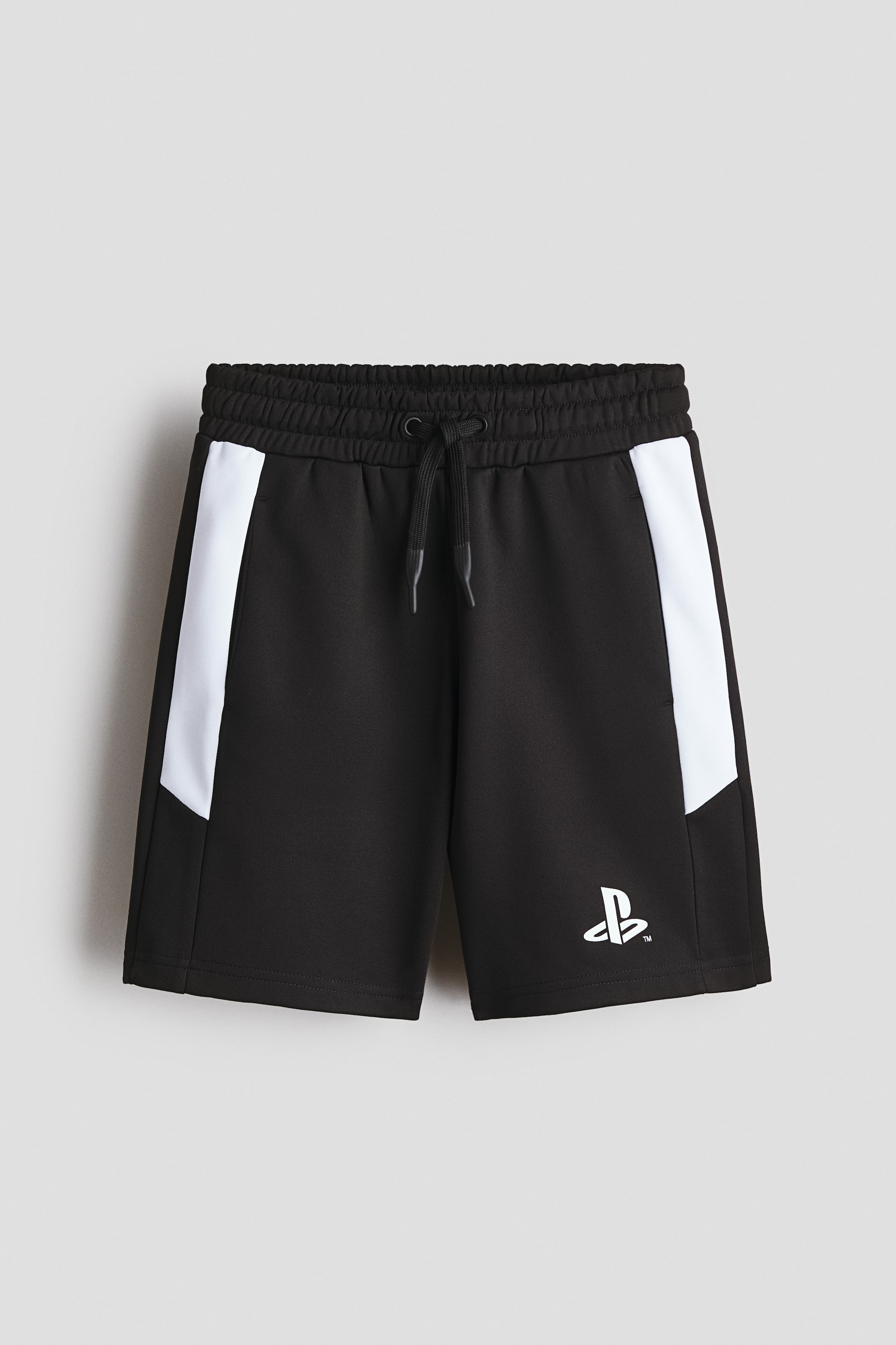 View larger image: The front of the black shorts features an elasticated waistband with a black drawstring, white angled panels running down each side, and a white PlayStation logo on the lower left leg.