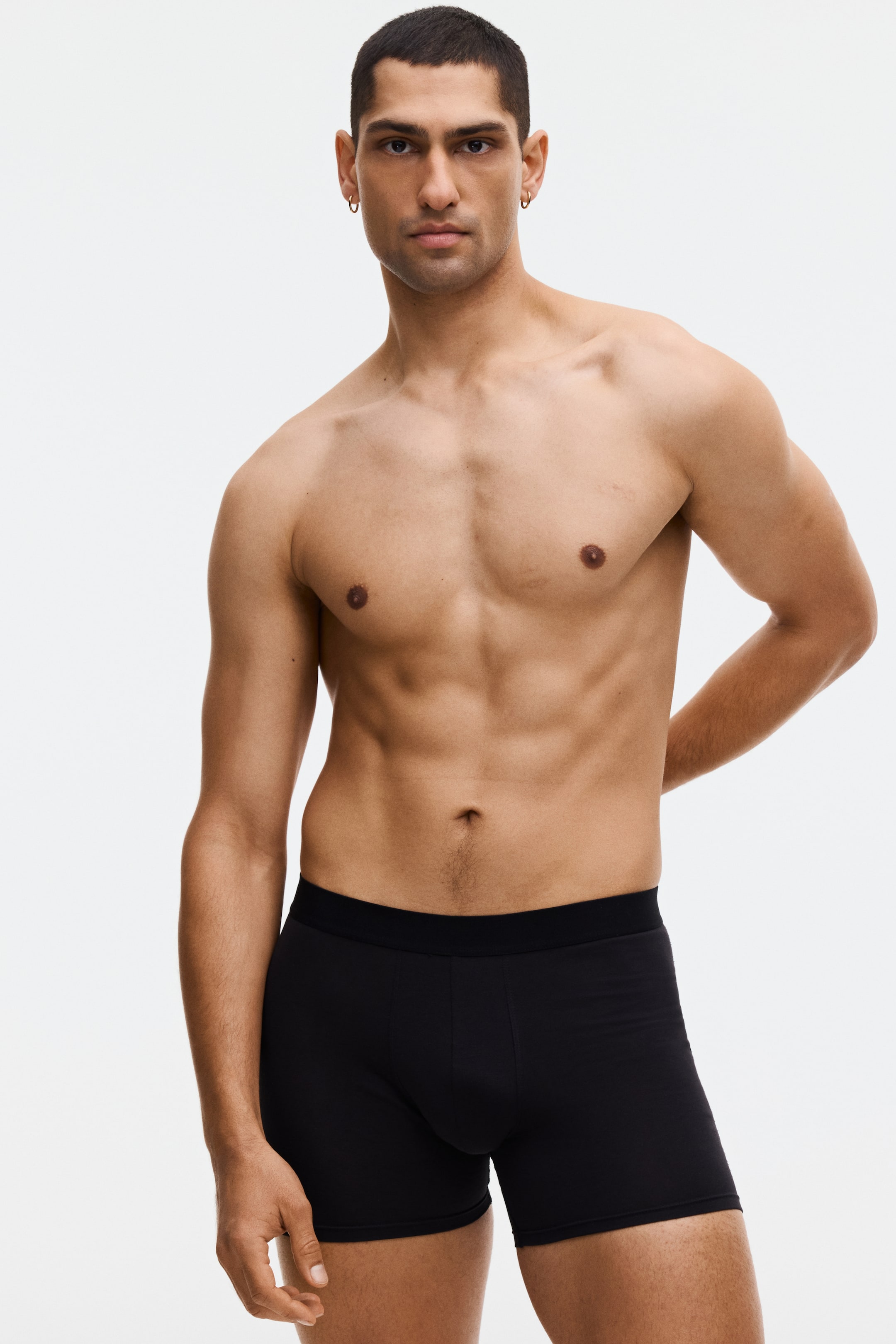 Grotere afbeelding bekijken: Zwarte boxershorts met een brede elastische tailleband en een gevormd voorvak. Ze sluiten nauw aan op het lichaam en worden gepresenteerd vanuit een licht schuine vooraanzicht links.