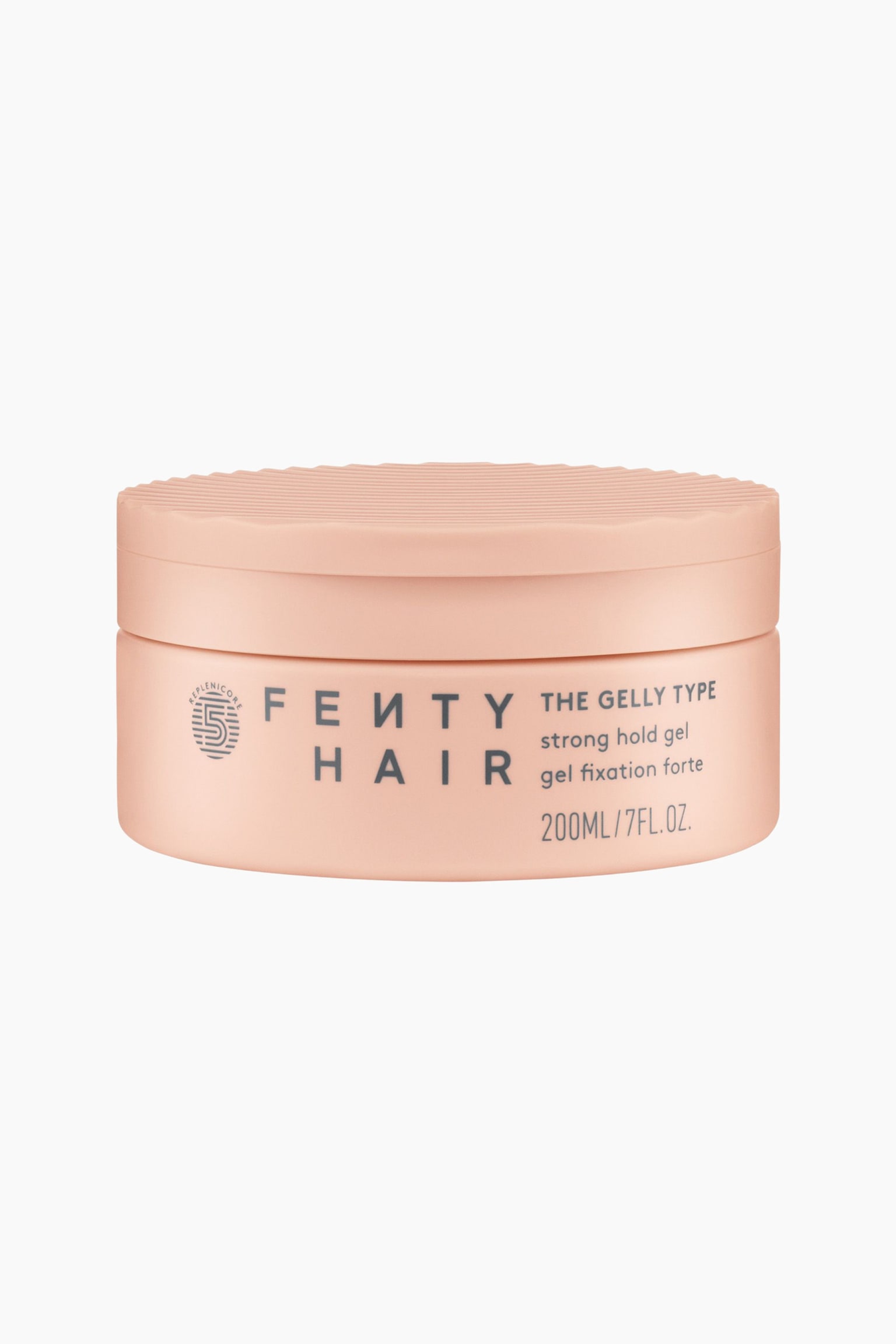 Gelly Type Strong Hold Gel on etupuolelta kuvattuna, ja se esitetÃ¤Ã¤n mattapintaisena persikanvÃ¤risenÃ¤ sylinterimÃ¤isenÃ¤ purkkina, jossa on teksturoitu, uritettu kansi. Astian etupuolella nÃ¤kyy âFenty Hairâ -logo, pyÃ¶reÃ¤ tunnus sekÃ¤ tuotetiedot, mukaan lukien âThe Gelly Type strong hold gelâ tummanharmaalla tekstillÃ¤.