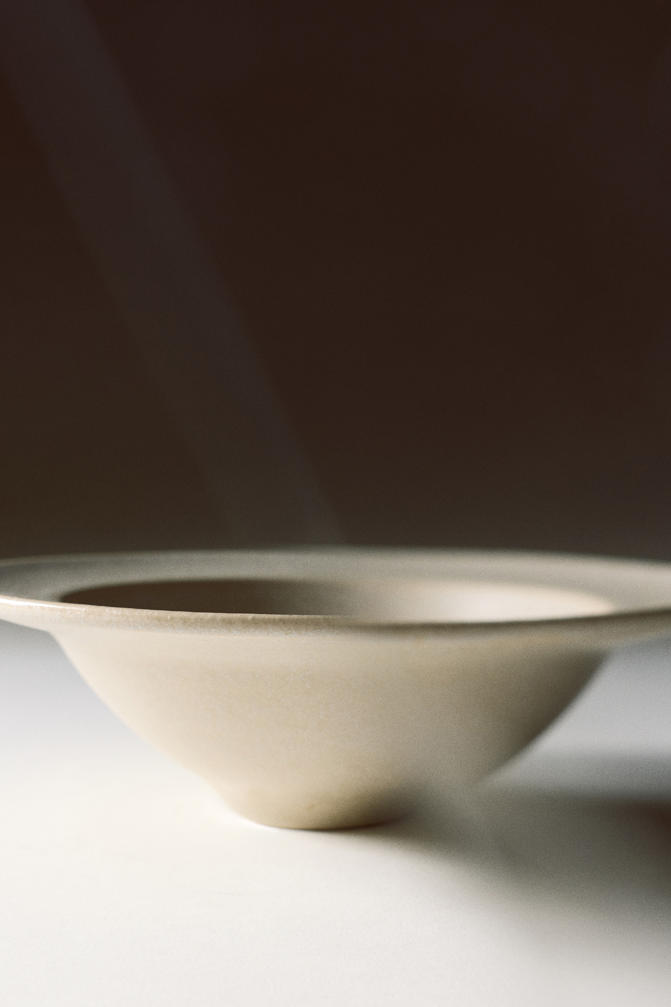 Due ciotole in ceramica bianco sporco sono posizionate una accanto allâaltra, mettendo in risalto una forma conica rastremata che si apre verso un bordo ampio e piatto. Le ciotole presentano una smaltatura opaca, finemente testurizzata, e sono mostrate da un angolo frontale.