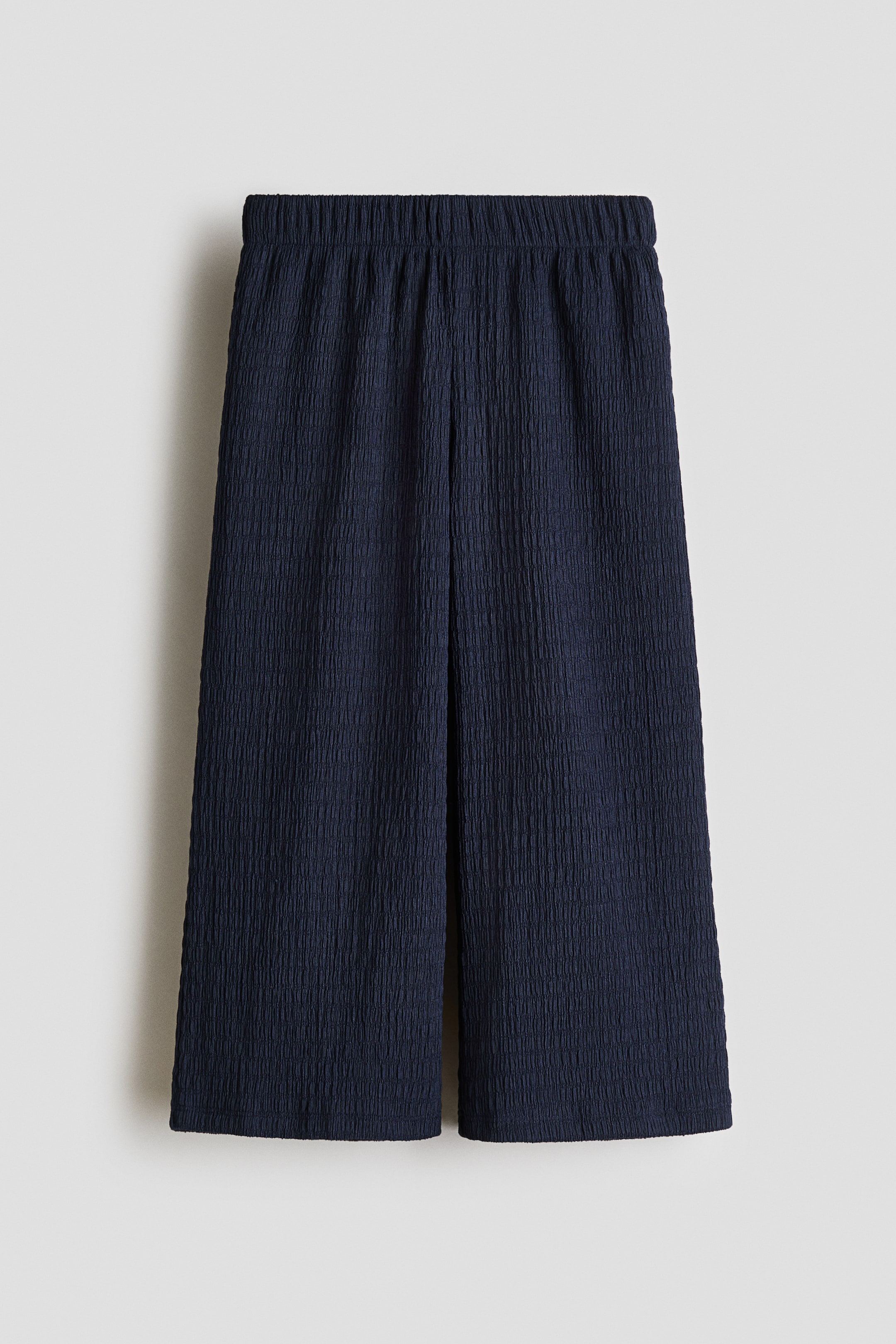View larger image: Dark blue wide-leg pants na may crinkled texture sa kabuuan at elasticated waistband, na nagpapakita ng cropped silhouette mula sa harap.