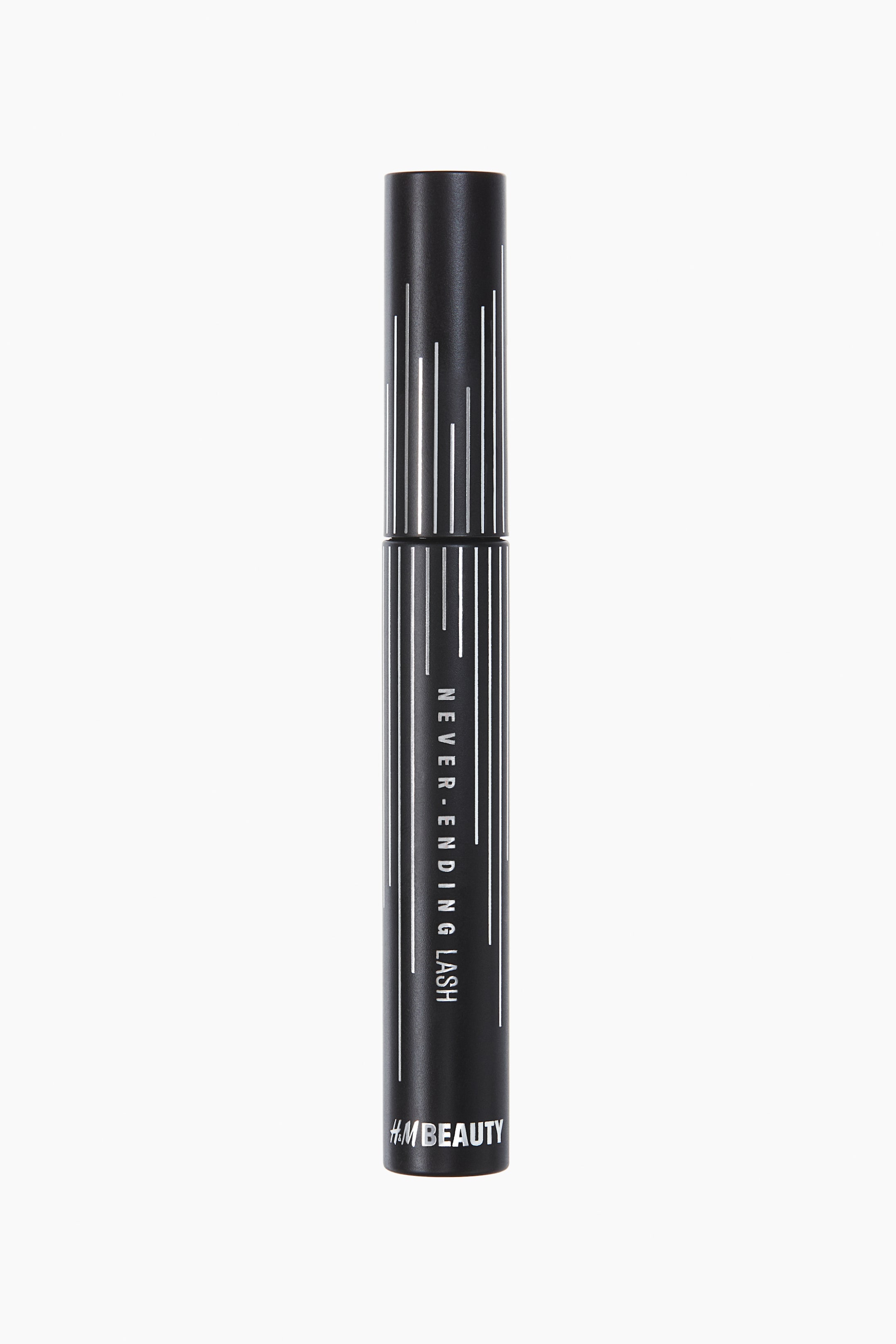 View larger image: A front-facing, matte black cylindrical mascara tube is standing upright. White vertical lines are decorating the top and bottom halves, originating from a narrow silver band at the center. The text "NEVER-ENDING LASH" is running vertically down the front of the lower half, and "H&M BEAUTY" is visible horizontally near the bottom.