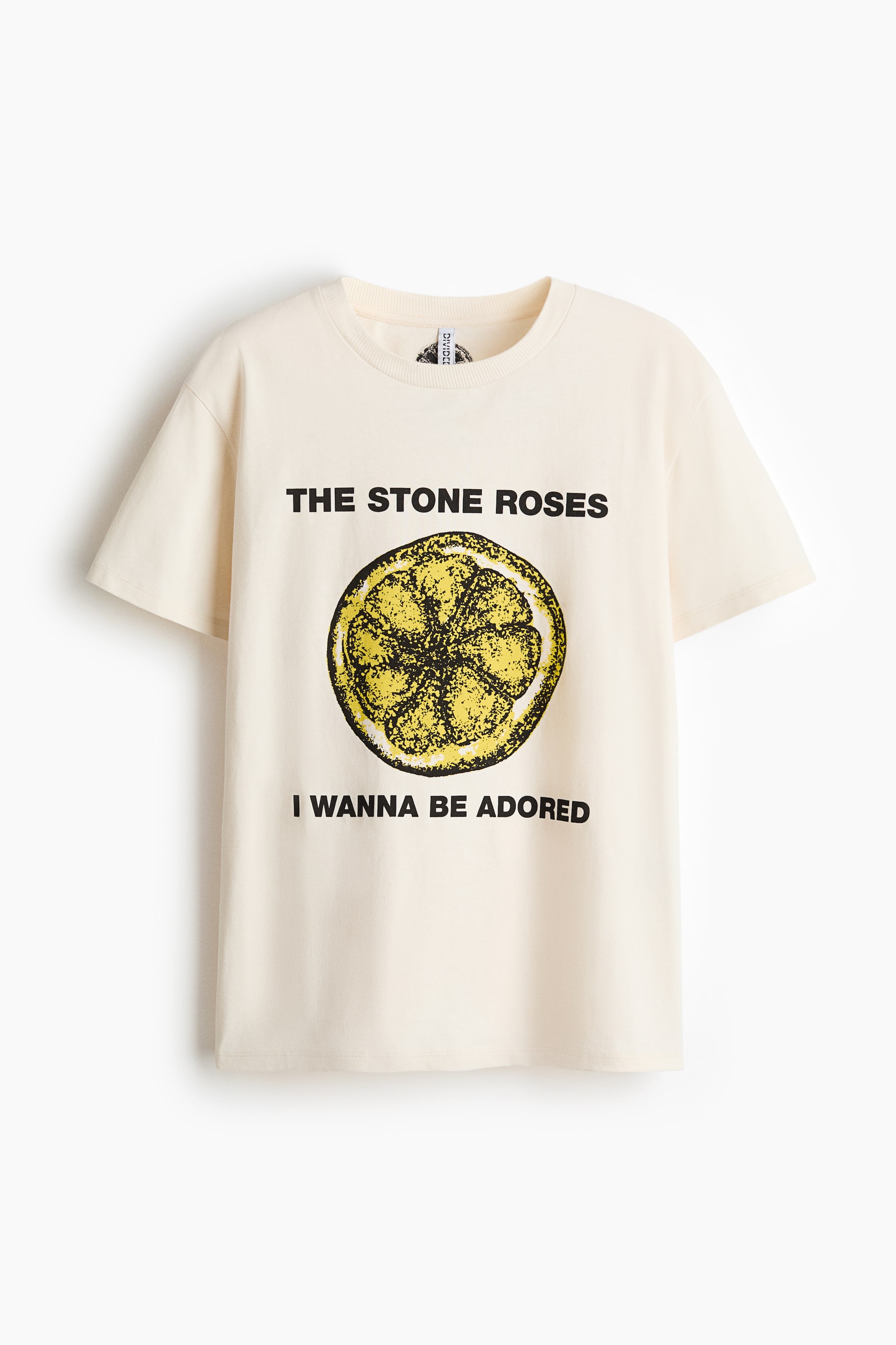 Größeres Bild ansehen: Ein cremefarbenes T-Shirt zeigt seine Vorderseite mit einem gerippten Rundhalsausschnitt und kurzen Ärmeln. Es präsentiert eine schwarze Grafik mit der Aufschrift "THE STONE ROSES" über einer gelb-schwarz stilisierten Zitronenscheibe, darunter "I WANNA BE ADORED".