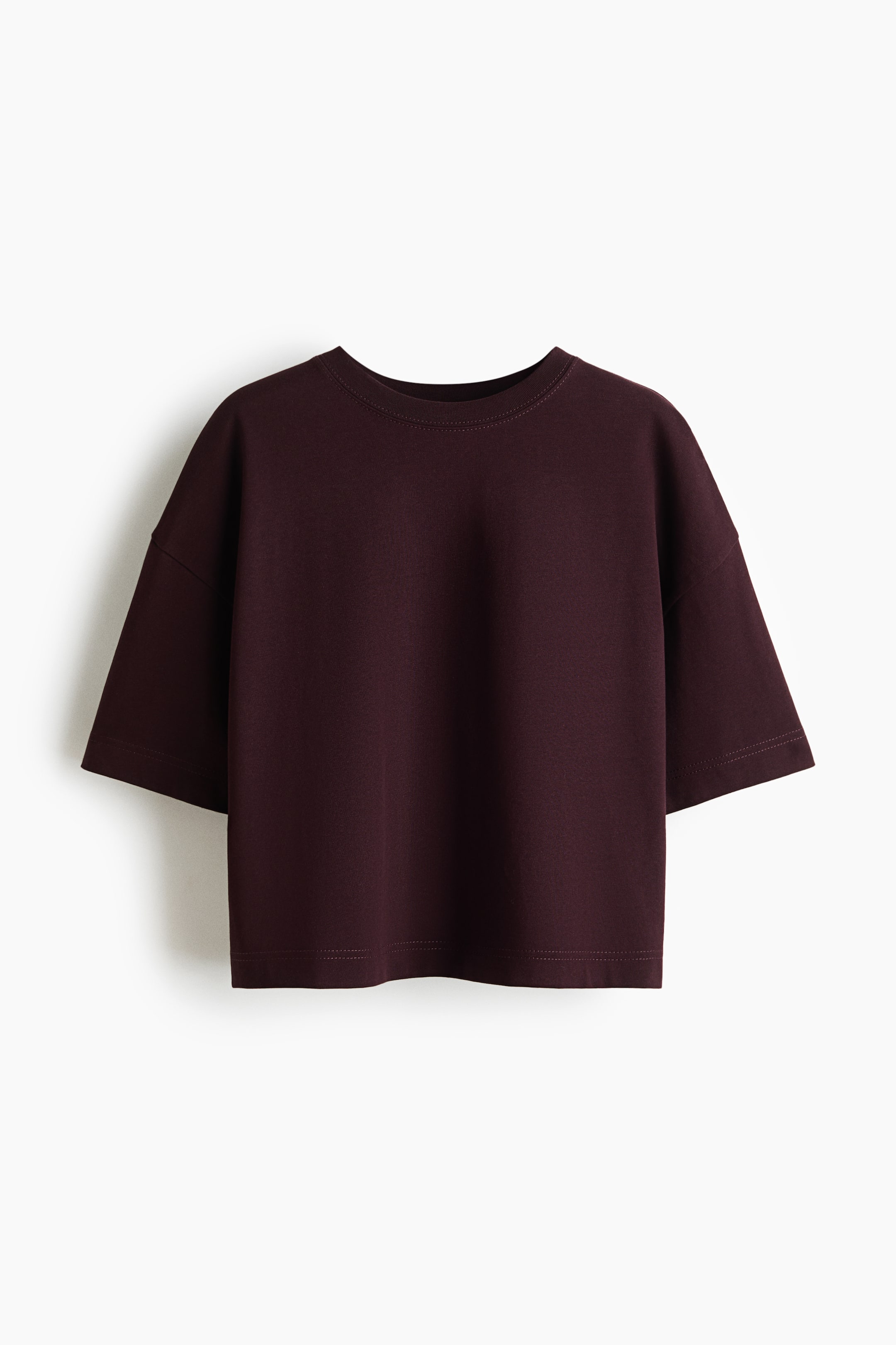 View larger image: A dark red crew neck t-shirt features dropped shoulders and short, wide sleeves. It showcases a smooth texture and a cropped length with a straight hem, presented facing forward.