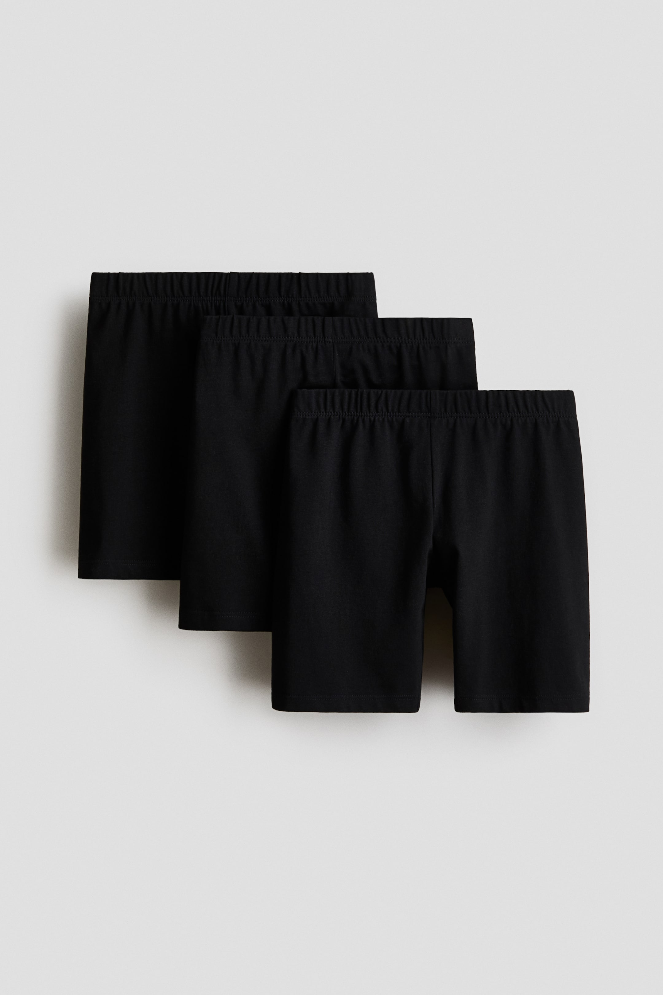 View larger image: Three pairs of black shorts are displayed in a layered arrangement, with each pair featuring an elastic waistband at the front.