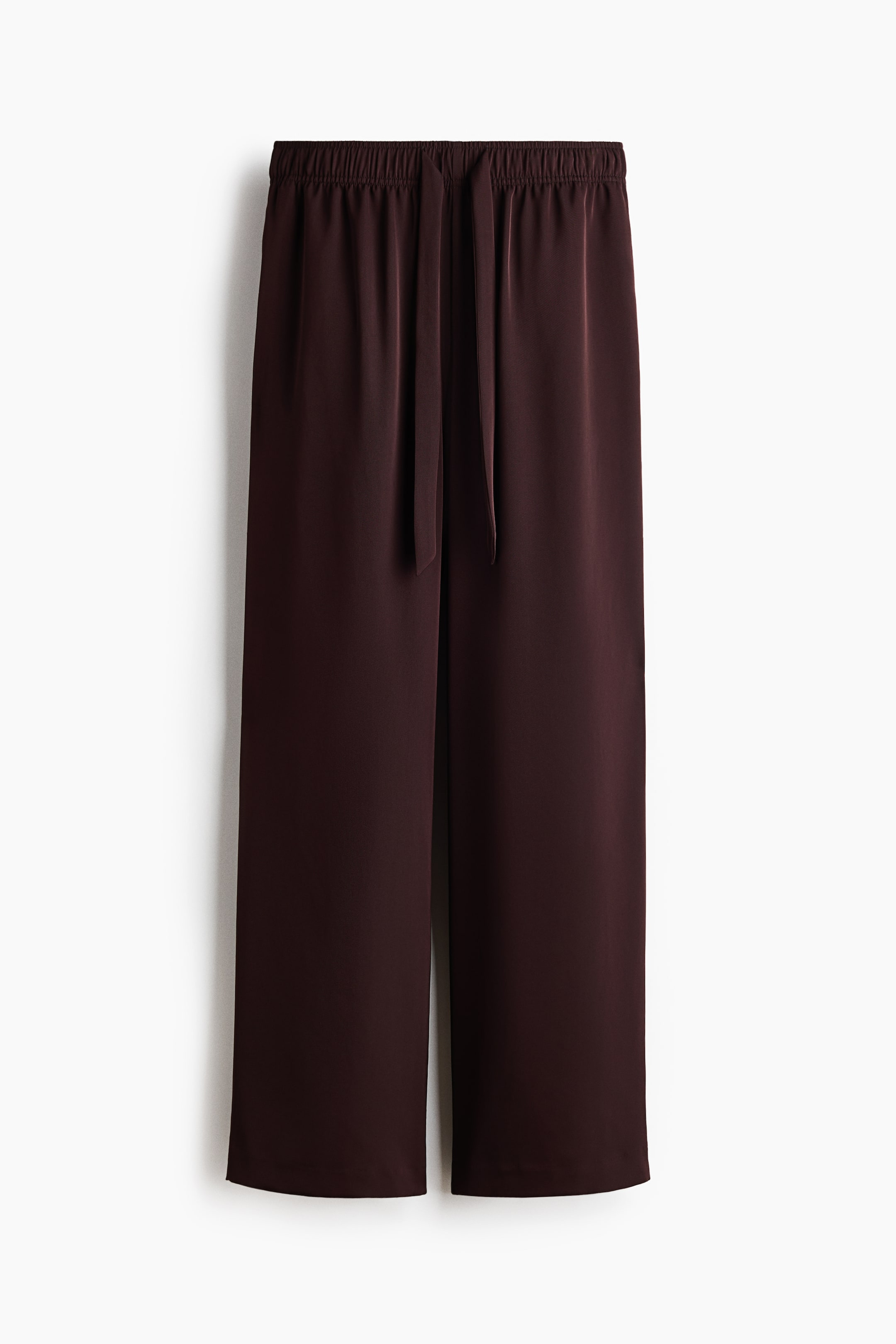 View larger image: Dark brown wide-leg pants showcase a front view with an elasticized waistband and a matching drawstring tie. The smooth fabric drapes fluidly.