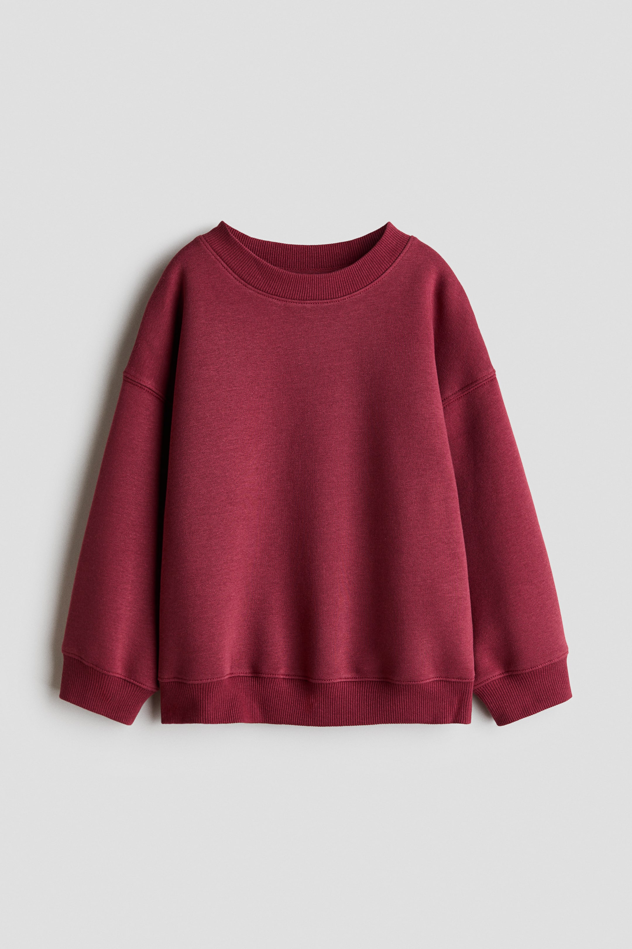 View larger image: A deep red sweatshirt is laid flat, facing forward, featuring a crew neck, ribbed cuffs, and a ribbed hem.