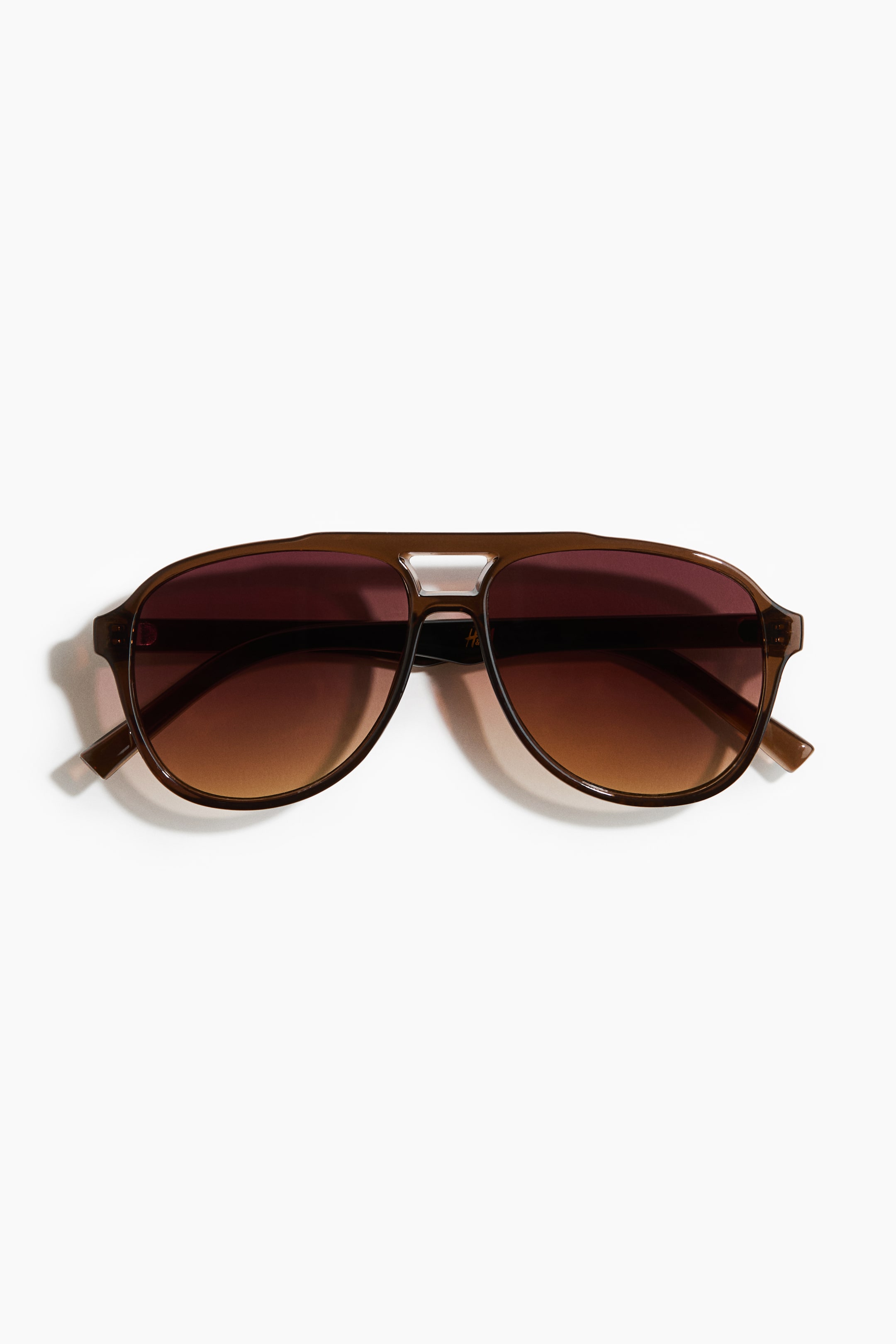 View larger image: Aviator-style sunglasses showcase brown plastic frames with a double bridge design. The tinted, gradient UV-protective lenses appear darker at the top and lighter towards the bottom.
