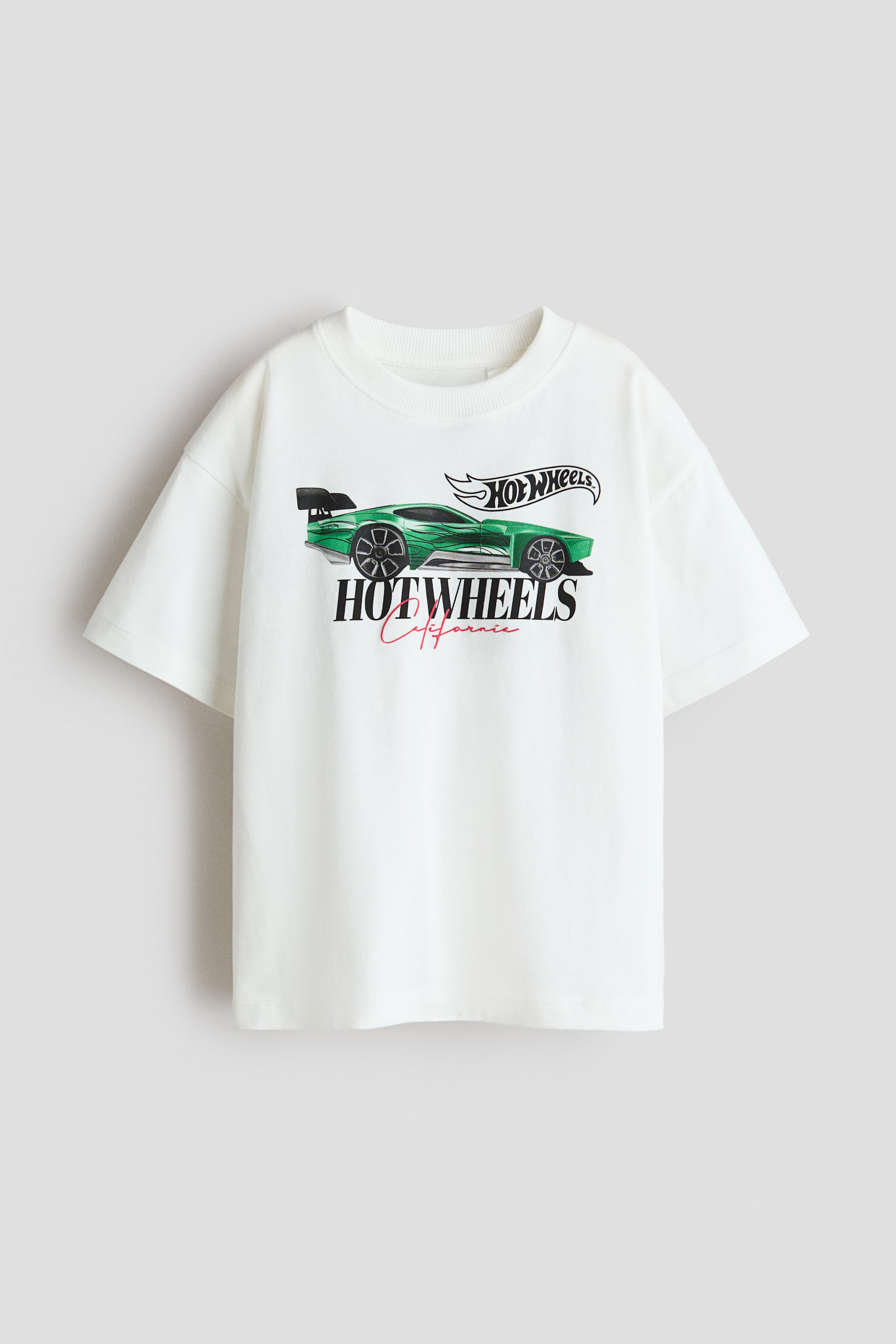 Ver imagem maior: Uma t-shirt de corte largo em jersey de algodão macio está a exibir a sua parte frontal, com uma impressão de um carro de corrida verde da Hot Wheels juntamente com a marca "Hot Wheels". É desenhada com uma gola redonda com acabamento em malha canelada e ombros descaídos.
