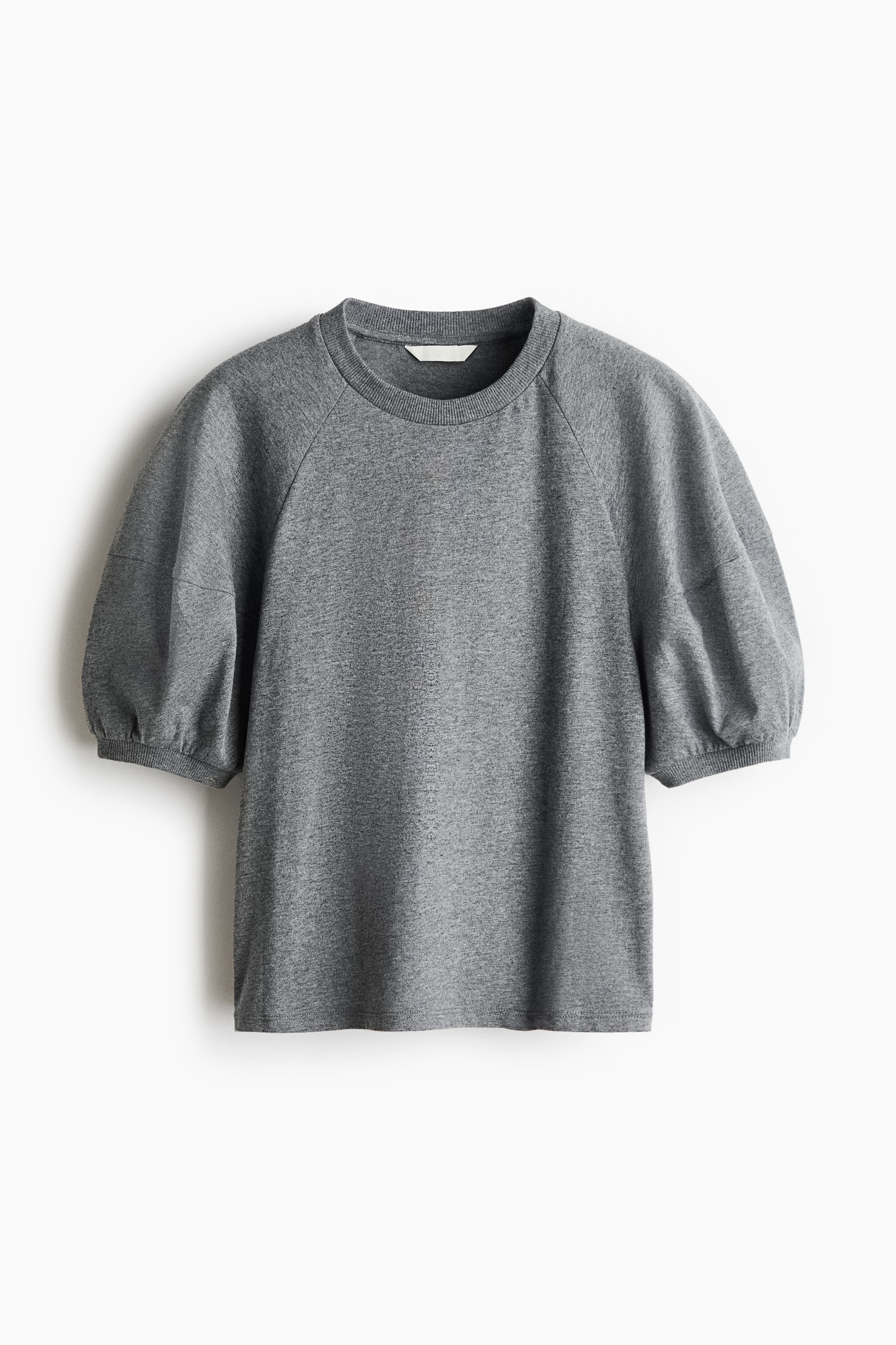 A grey cotton jersey top featuring a round, rib-trimmed neckline and short puff sleeves in a raglan cut with ribbed cuffs is being worn by the model. The top is paired with wide-leg, dark blue denim trousers.