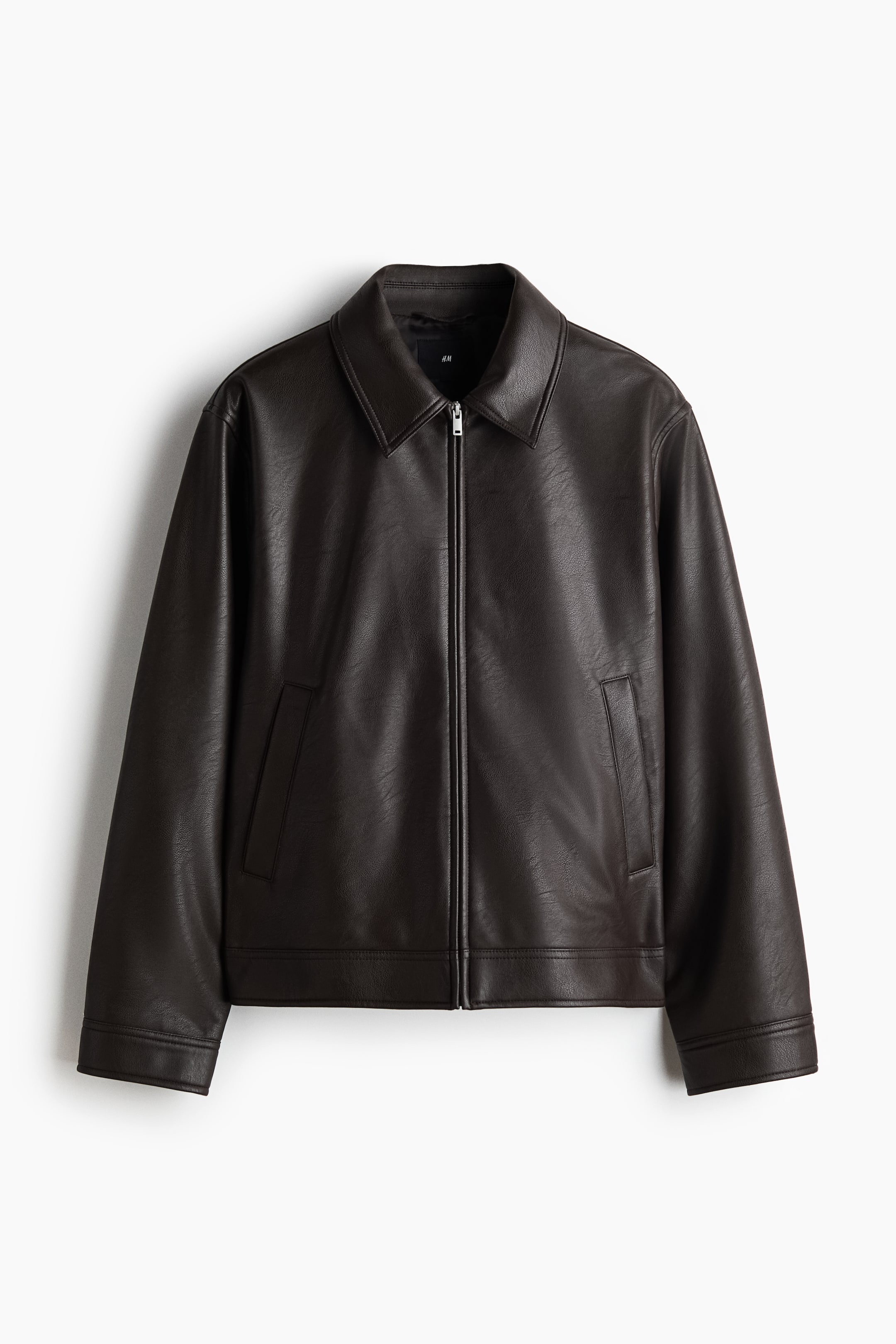 View larger image: The jacket is crafted from a dark brown coated fabric, showcasing a front view with a point collar and a central silver-toned zip closure. It includes two diagonal welt pockets on the front and straight cuffs fastened with a button.