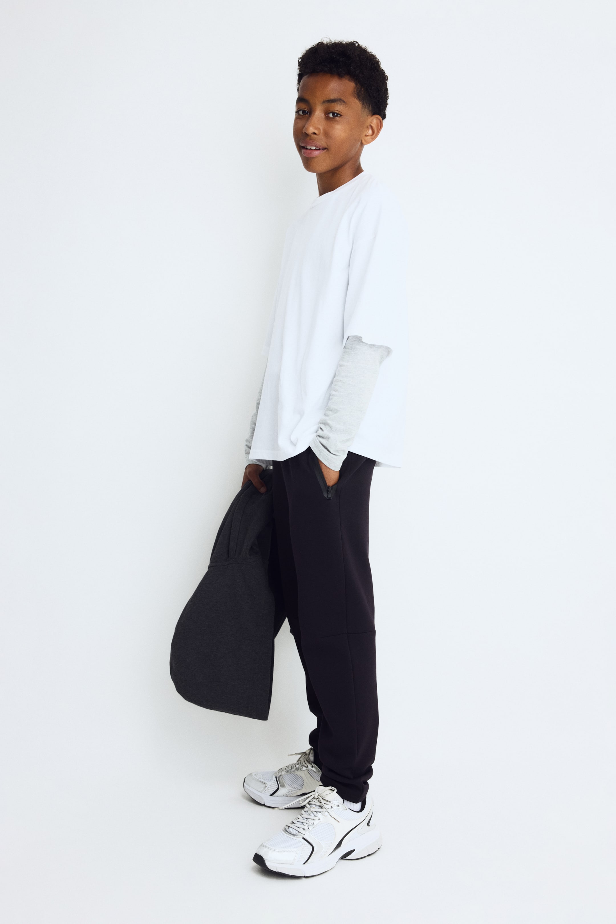 Visa större bild: Slim fit sportjoggers visas från en framsidesvinkel, med en svart färg och en sidoficka med dragkedja. Joggersen smalnar av längs benet till ribbade muddar vid anklarna.
