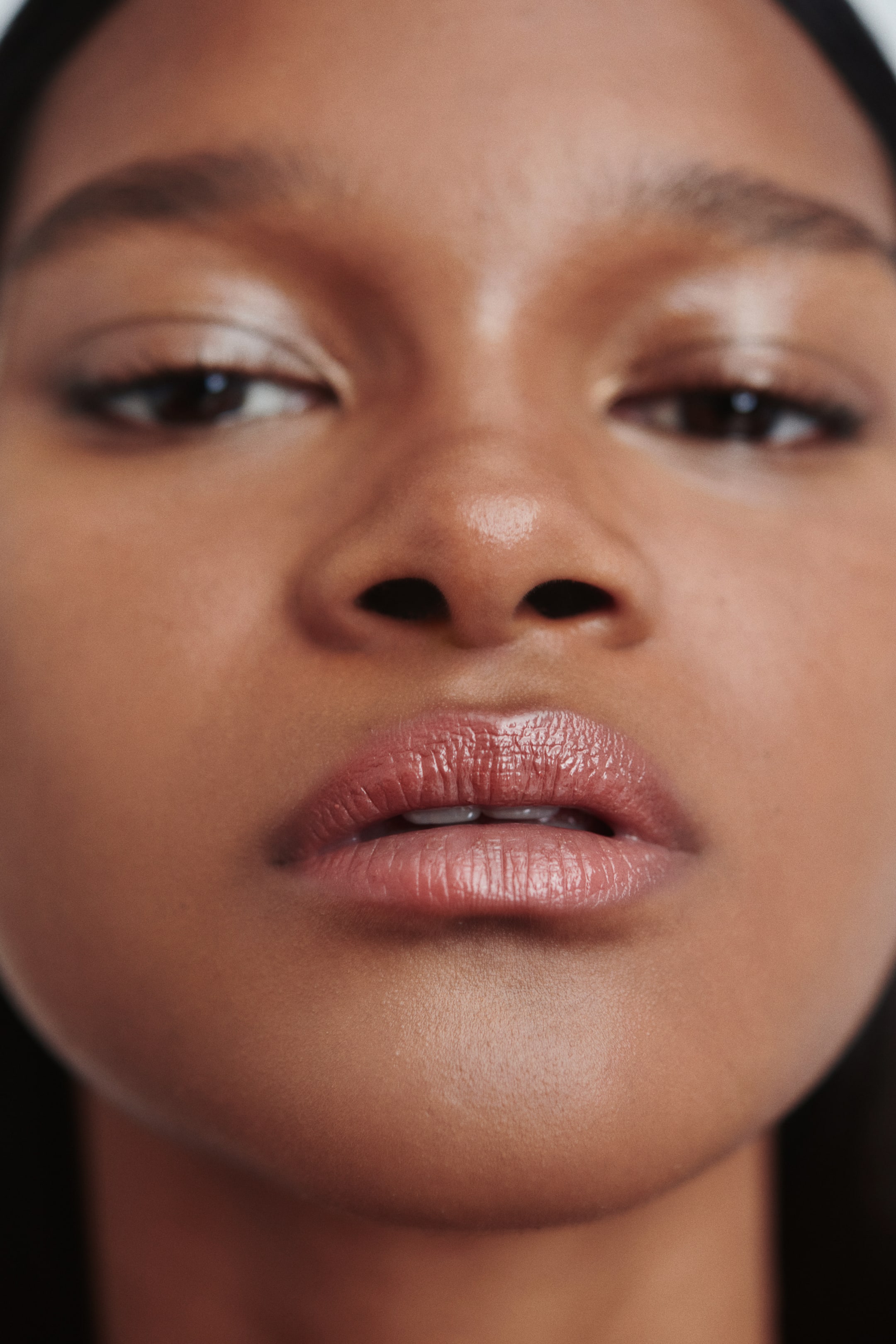 View larger image: A shimmering, brownish-pink lip colour is being worn on full, slightly parted lips, which are facing forward.
