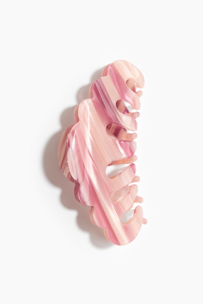 A hair claw clip is showcasing a marbled pattern in shades of light pink, mauve, and cream. The clip is displaying a curved design with interlocking teeth and a smooth, glossy finish, facing front to highlight its shape and structure. - 1