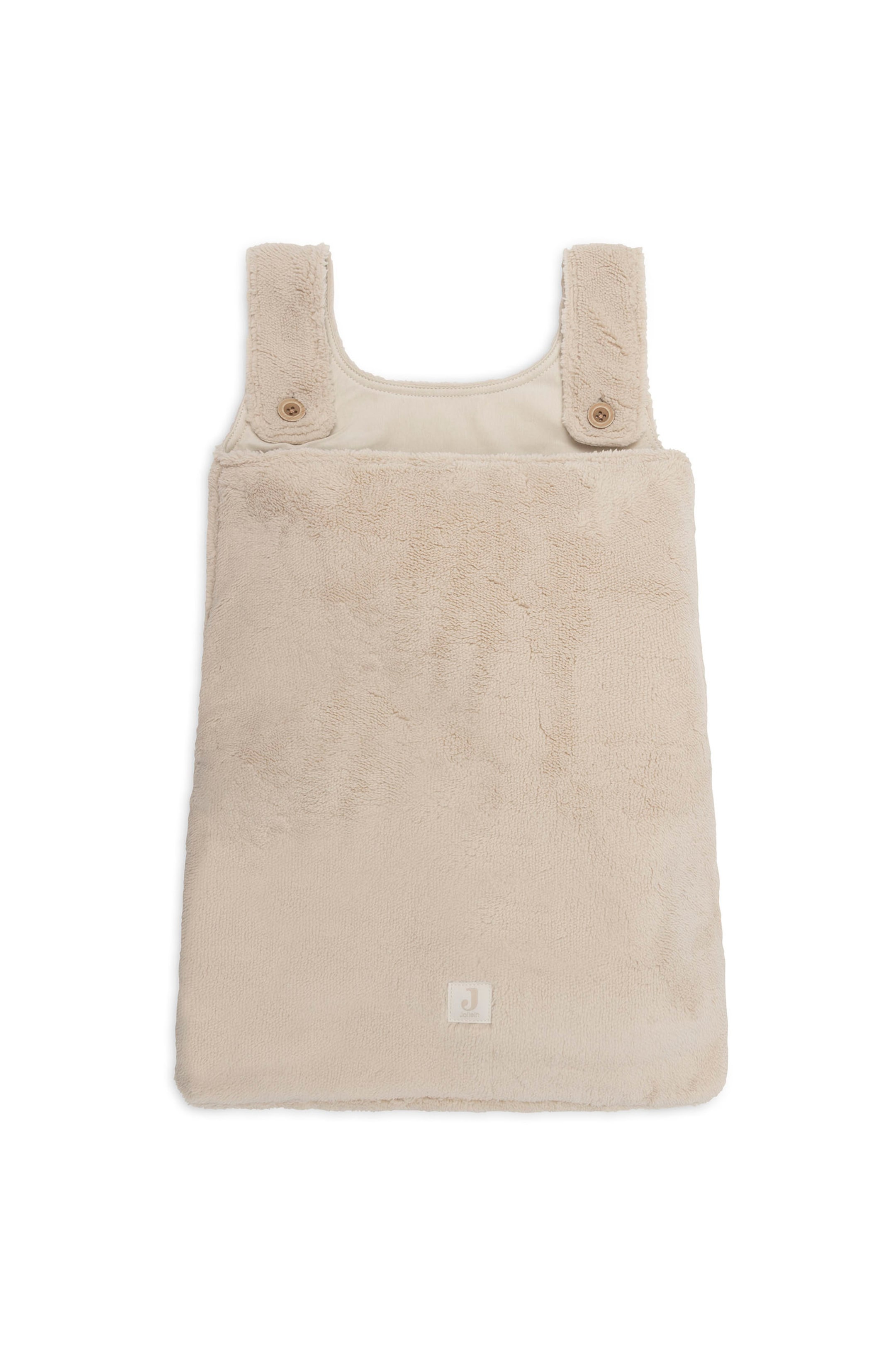 Grotere afbeelding bekijken: Een beige, zachte babyslaapzak ligt plat en is naar voren gericht, waarbij de zachte, pluizige fleece-textuur mooi zichtbaar is. Het mouwloze ontwerp heeft brede schouderbanden die aan de voorkant zijn vastgemaakt met enkele bruine knopen en een klein vierkant logopatchje dat dicht bij het midden aan de onderkant is vastgestikt.