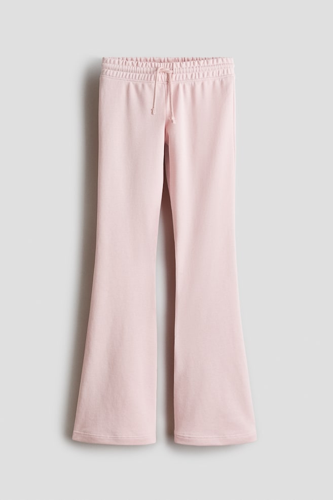 Pink joggers made from sweatshirt fabric feature an elasticated, drawstring waist and flared legs, shown from the front. - 1