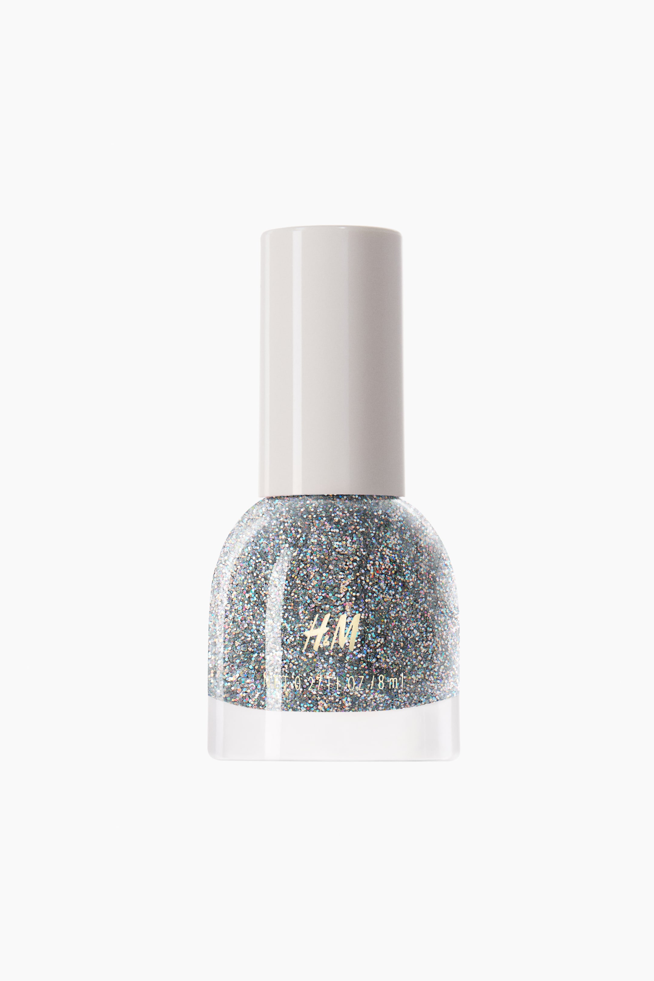 Agrandir l'image: Un flacon de vernis à ongles est présenté de face, contenant un glitter holographique argenté dense et scintillant à l’intérieur d’un flacon en verre arrondi. Le flacon est doté d’un bouchon cylindrique mat blanc cassé et affiche un lettrage de logo doré sur sa face avant.
