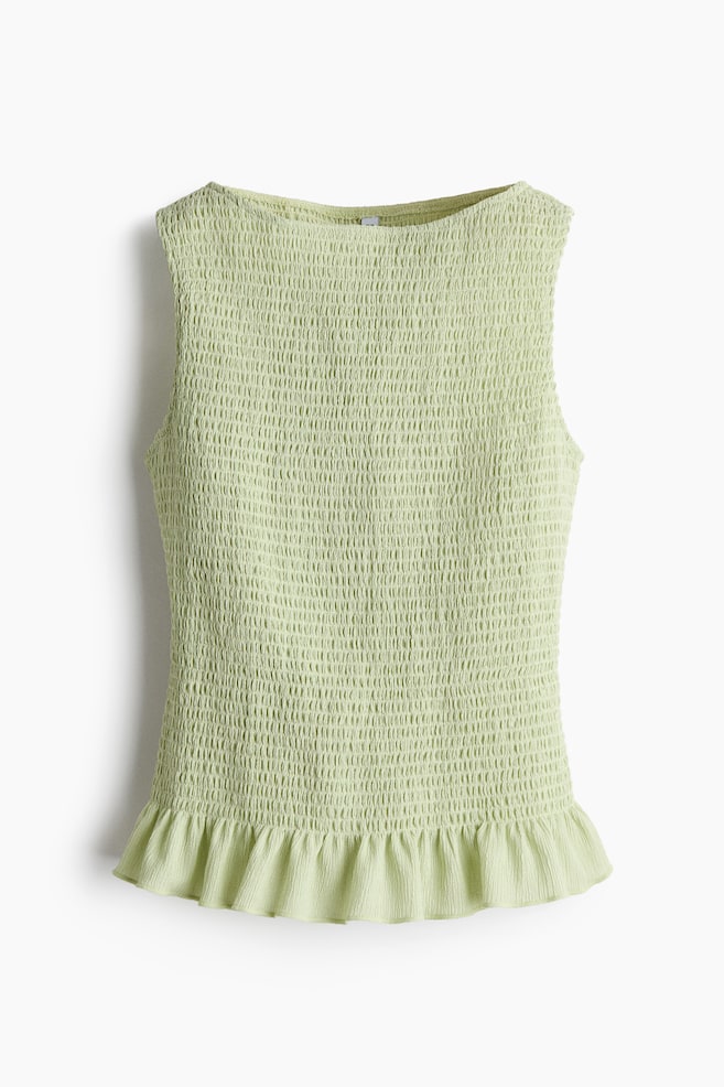 A light green sleeveless top is displayed front-on, featuring an all-over shirred texture from its wide neckline to its ruffled hem. - 1