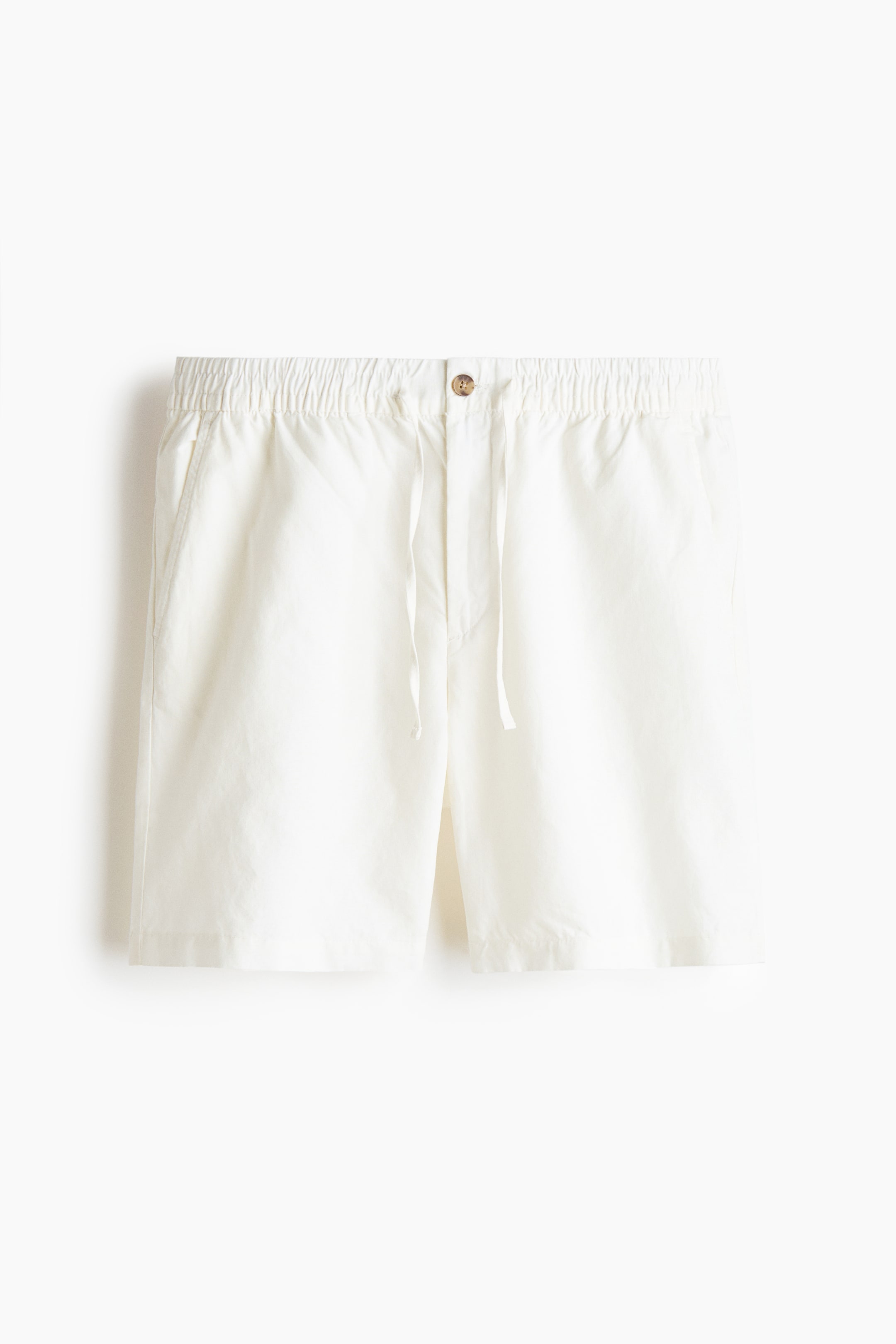 View larger image: White shorts are facing front, featuring an elasticized waistband with a drawstring closure, a single button, and visible side pockets.