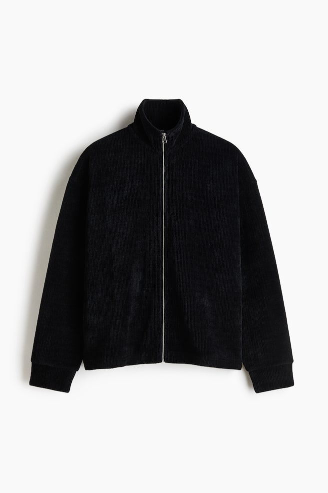 A black ribbed jacket with a corduroy-like texture is facing the front, featuring a full-length silver zipper, a high stand-up collar, and long sleeves with ribbed cuffs. - 1