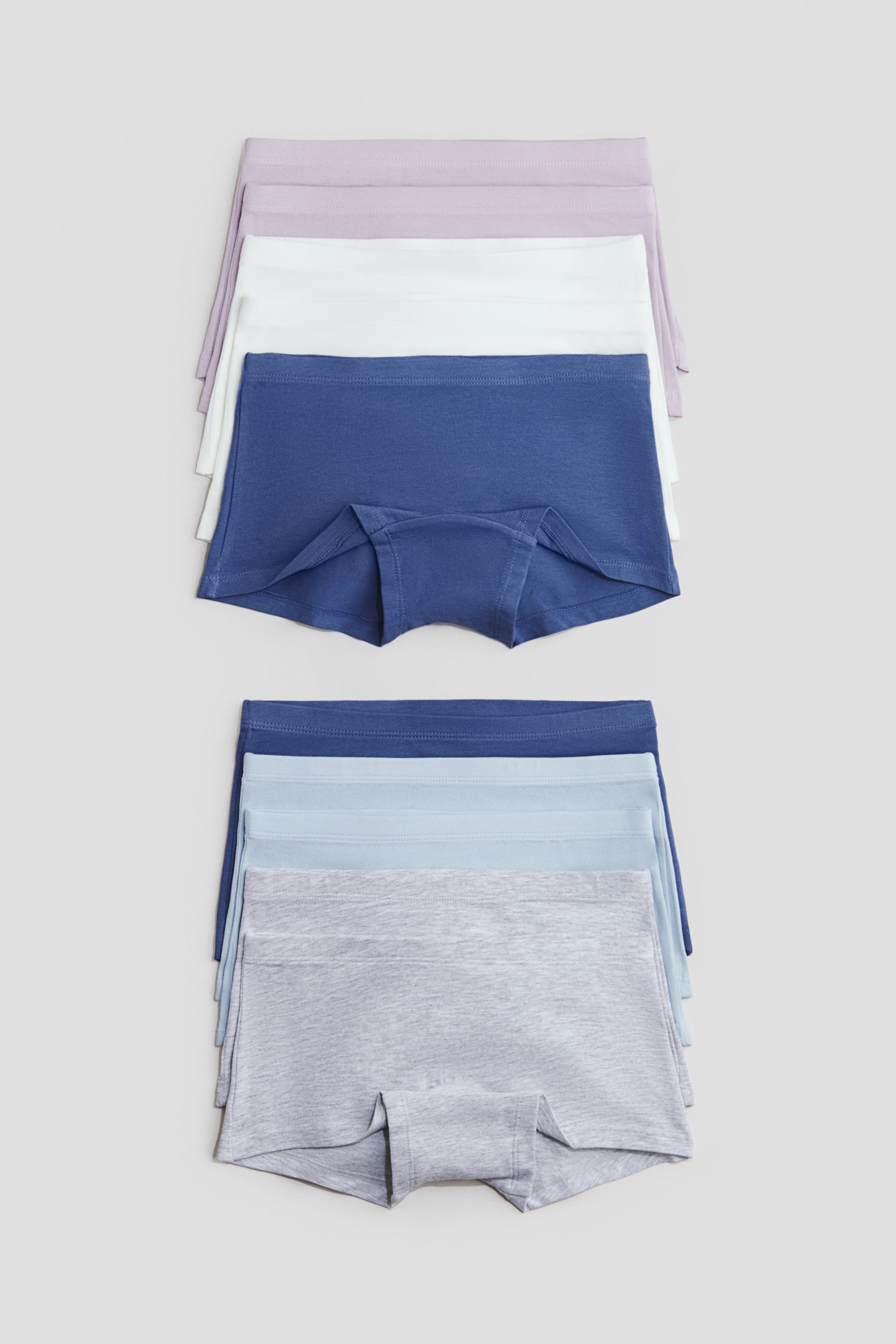 Se større billede: To stakke boksertrusser viser forskellige farver. Hvert par har blødt jerseystof og elastik i taljen, hvor fronten på den øverste boksertrusse i hver stak fremhæver en foret skridtindsats.