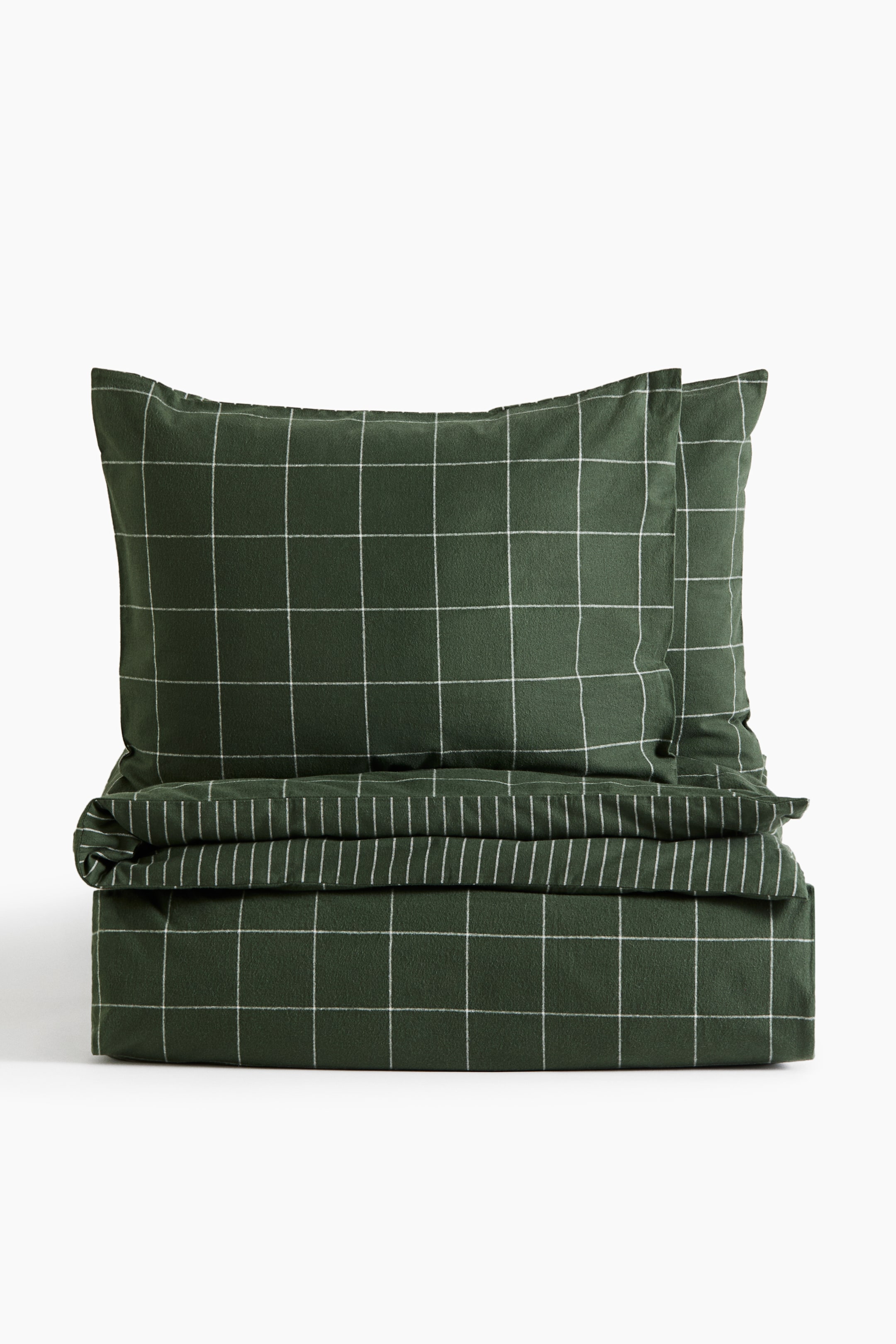 View larger image: A dark green cotton flannel quilt cover set is displayed from a front-facing angle, featuring a white windowpane grid pattern. The set showcases two upright pillowcases positioned behind a neatly folded quilt cover, highlighting the matching design and soft texture.