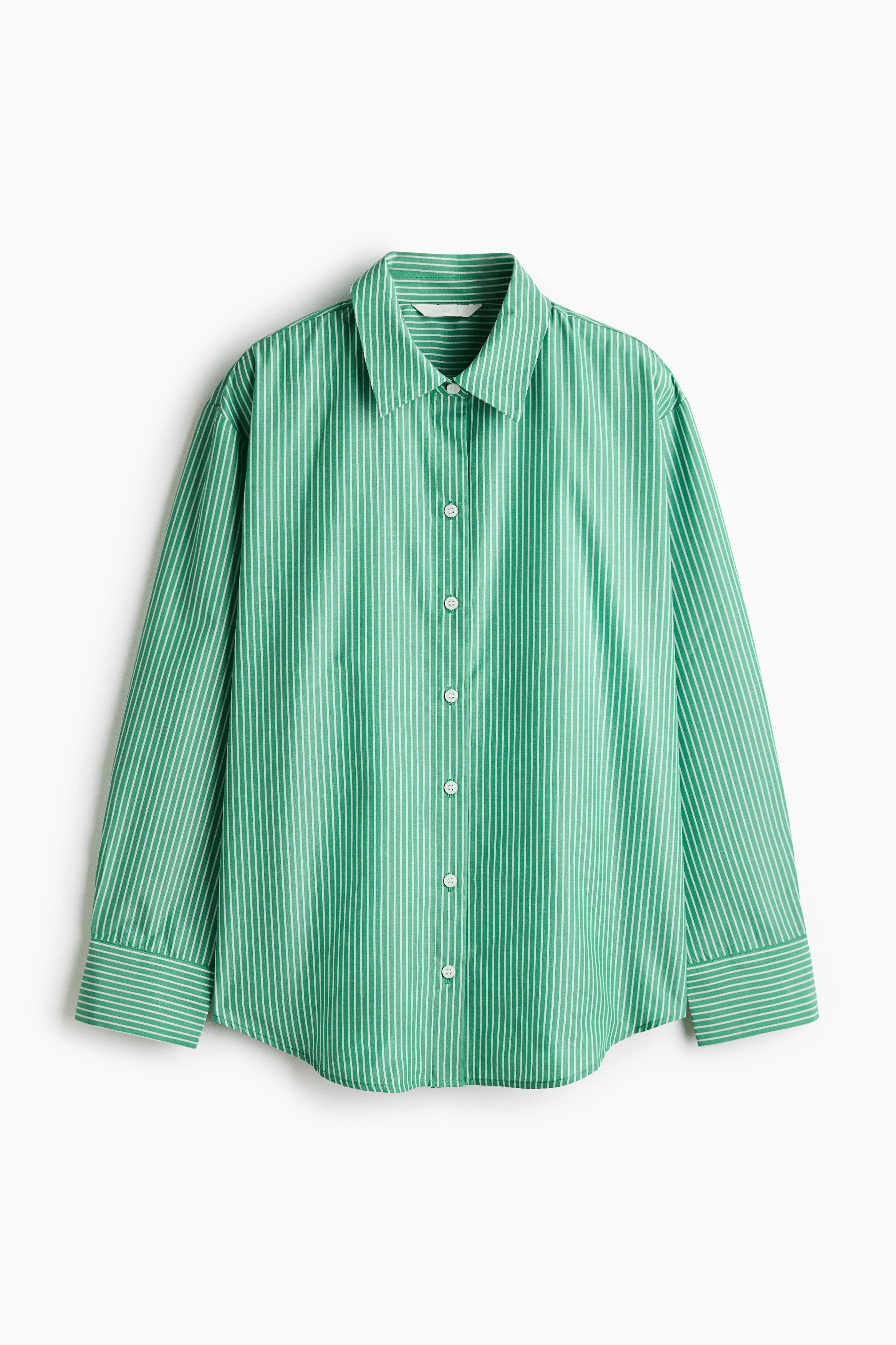 A green and white vertically striped woven shirt with a collar and front buttons is worn by the model, who is holding the collar with both hands. The long-sleeved shirt is styled with blue jeans and a red sweater tied around the waist.