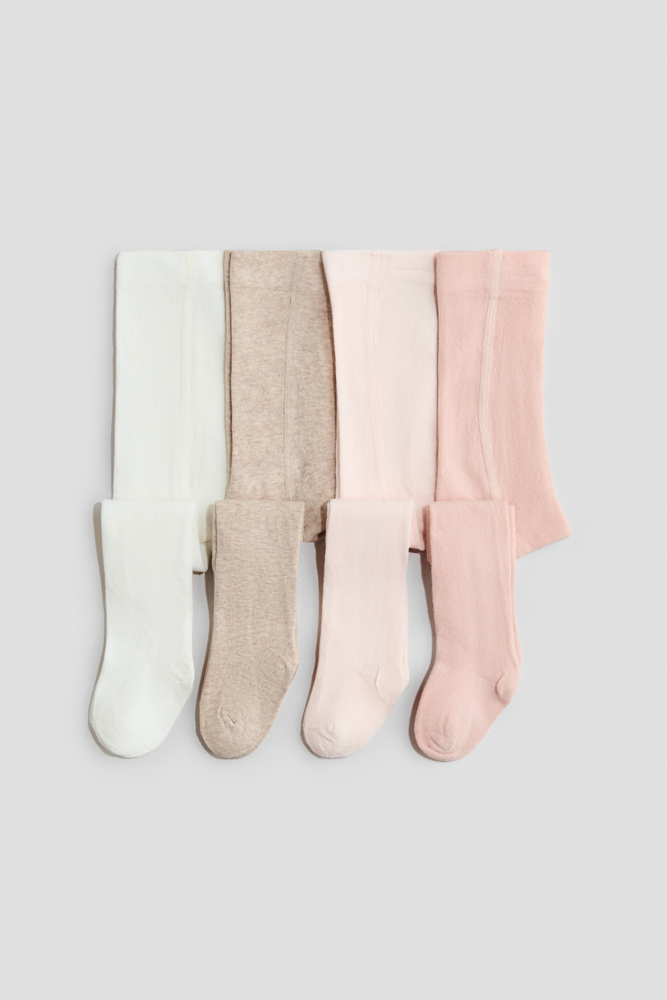 Agrandir l'image: Quatre paires de collants, confectionnées dans un mélange de coton doux et finement tricoté avec une taille élastiquée, sont exposées. Chaque paire est présentée à plat et pliée, montrant son devant dans les couleurs blanc, beige, rose clair et rose plus foncé.
