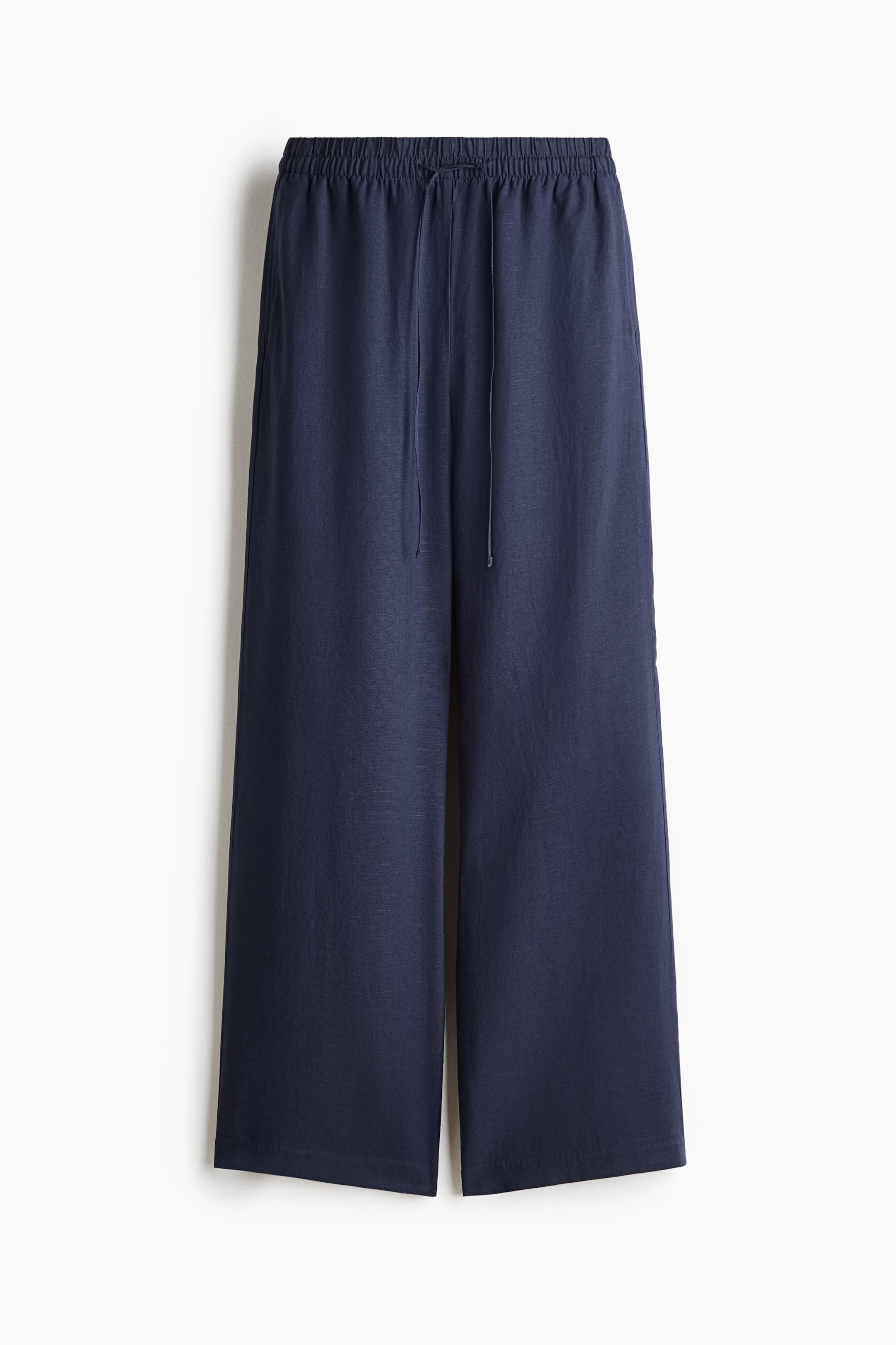 Agrandir l'image: Pantalon ample bleu marine, confectionné dans un mélange de lin avec un tissage aéré, présenté en vue de face. Il est doté d'une taille haute élastiquée avec un cordon de serrage fin, de poches latérales discrètes et de jambes larges et droites.