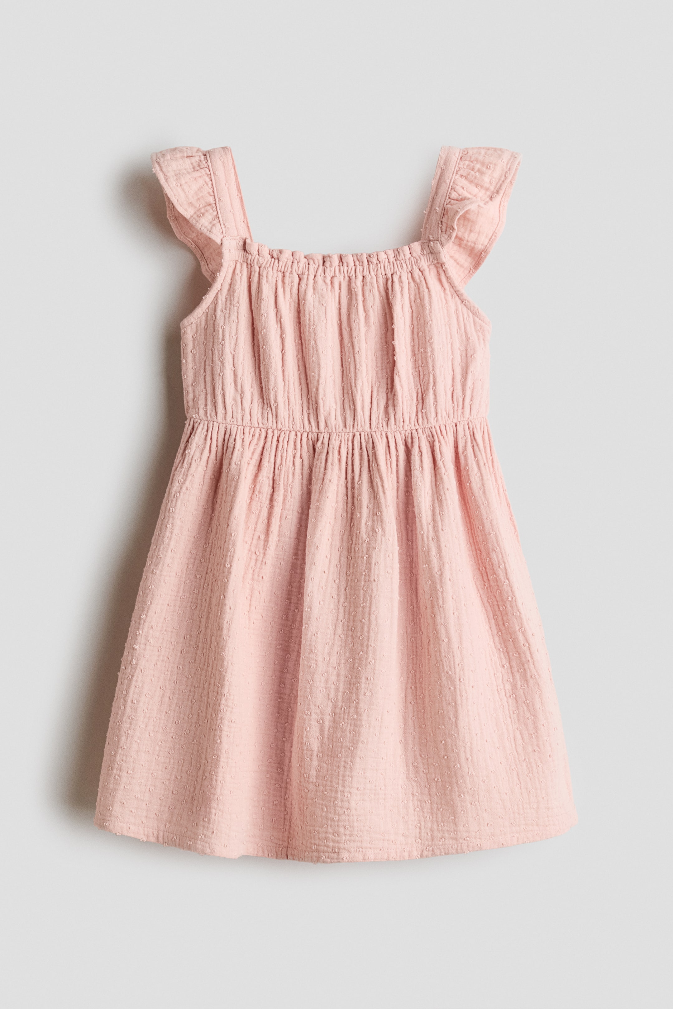 View larger image: This pink dress features a square neckline with ruffled shoulder straps, a gathered elasticated bodice, and an A-line skirt. The entire dress showcases a crinkled texture with subtle raised dots.