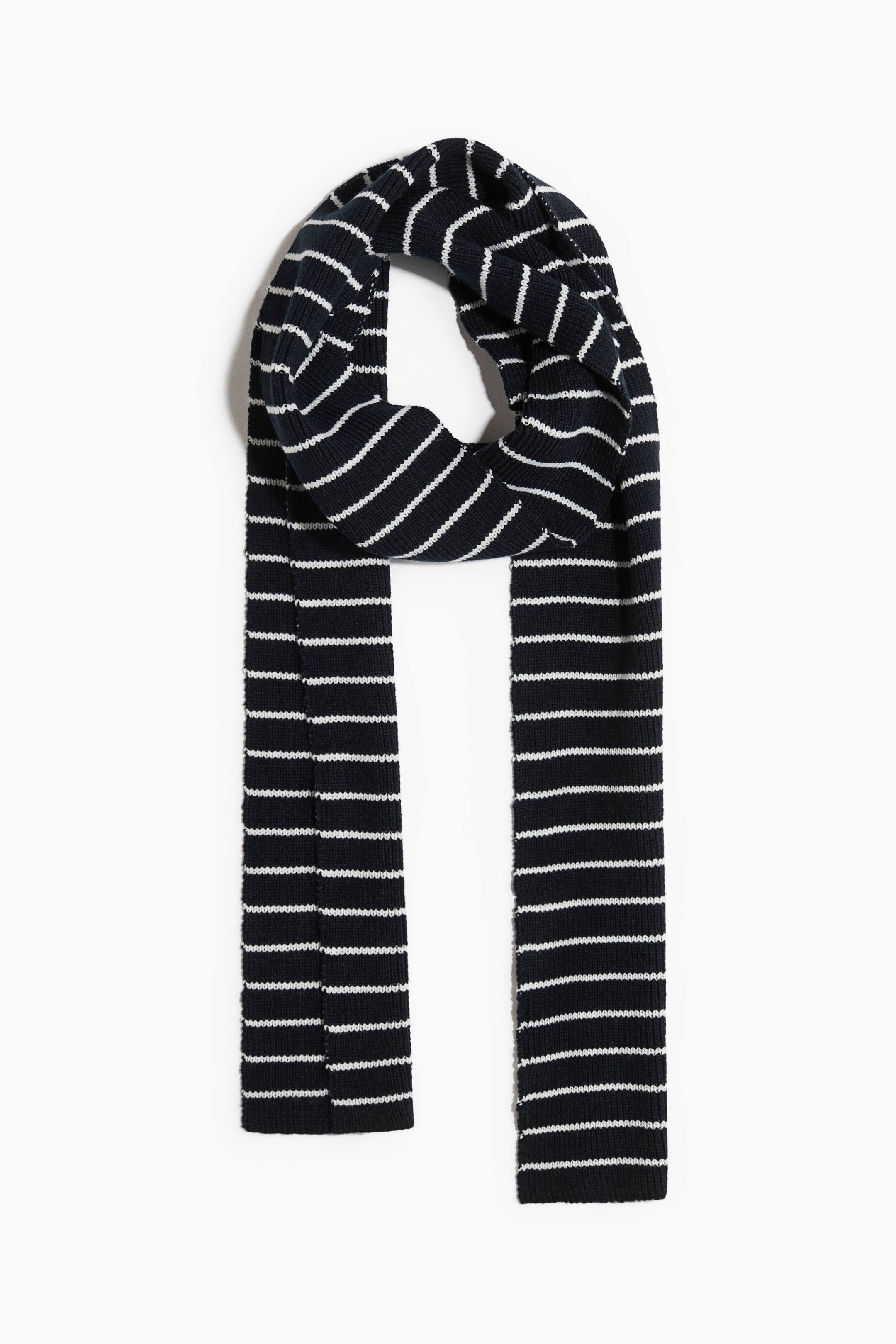 Grösseres Bild ansehen: Ein marineblauer und weisser Strickschal hängt frontal, mit einer lockeren Schlaufe oben und zwei langen Enden, die gerade nach unten fallen. Der Schal zeigt eine gerippte Struktur mit abwechselnden horizontalen Streifen.