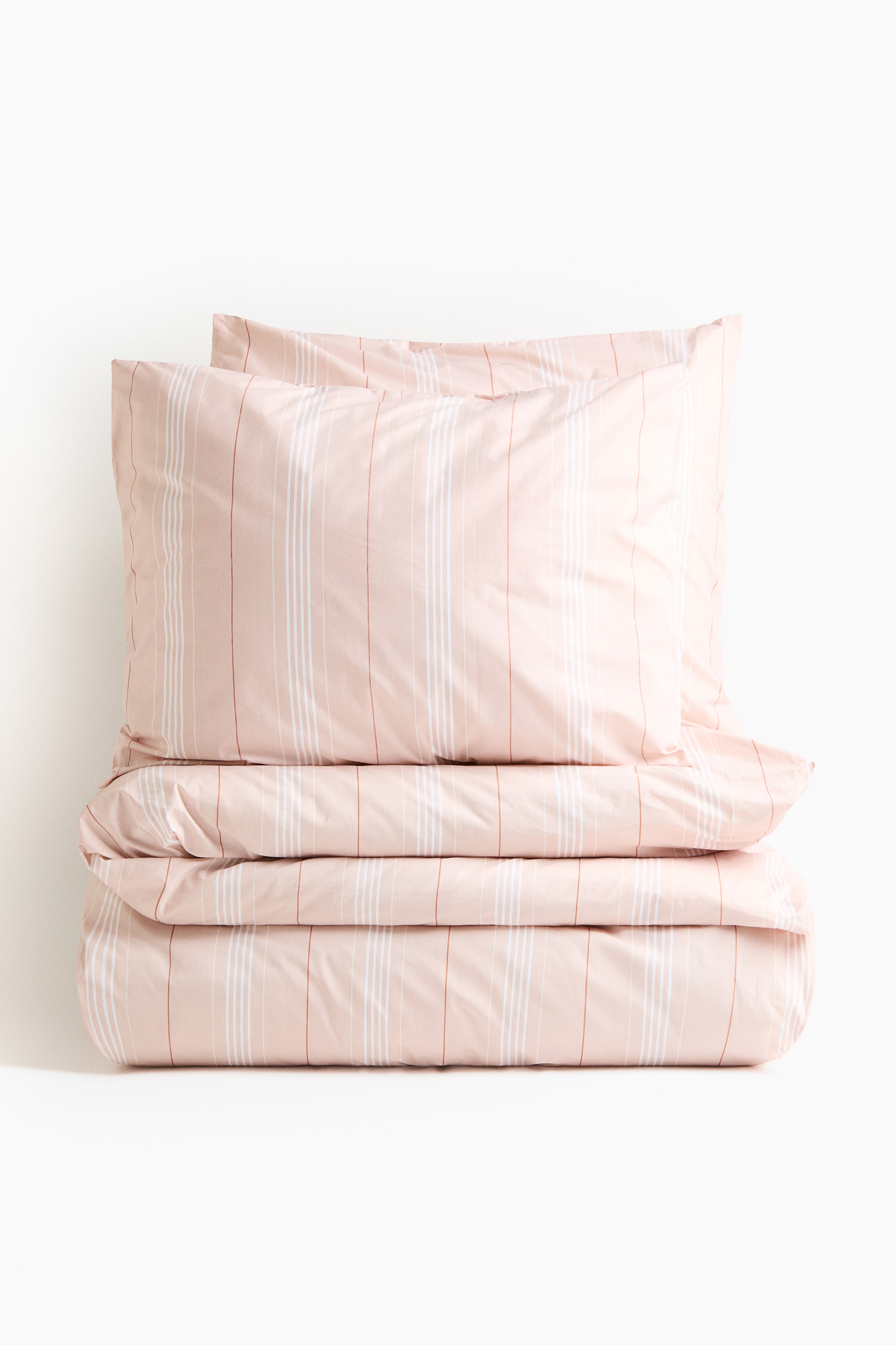 拡大画像を表示: 掛け布団カバーセットは正面からのビューで紹介されています。折りたたまれた掛け布団カバーと、その上に積み重ねられた2つの枕カバーがあり、すべてがライトピンク色で縦に白と赤茶色のストライプがあり、艶消し仕上げになっています。