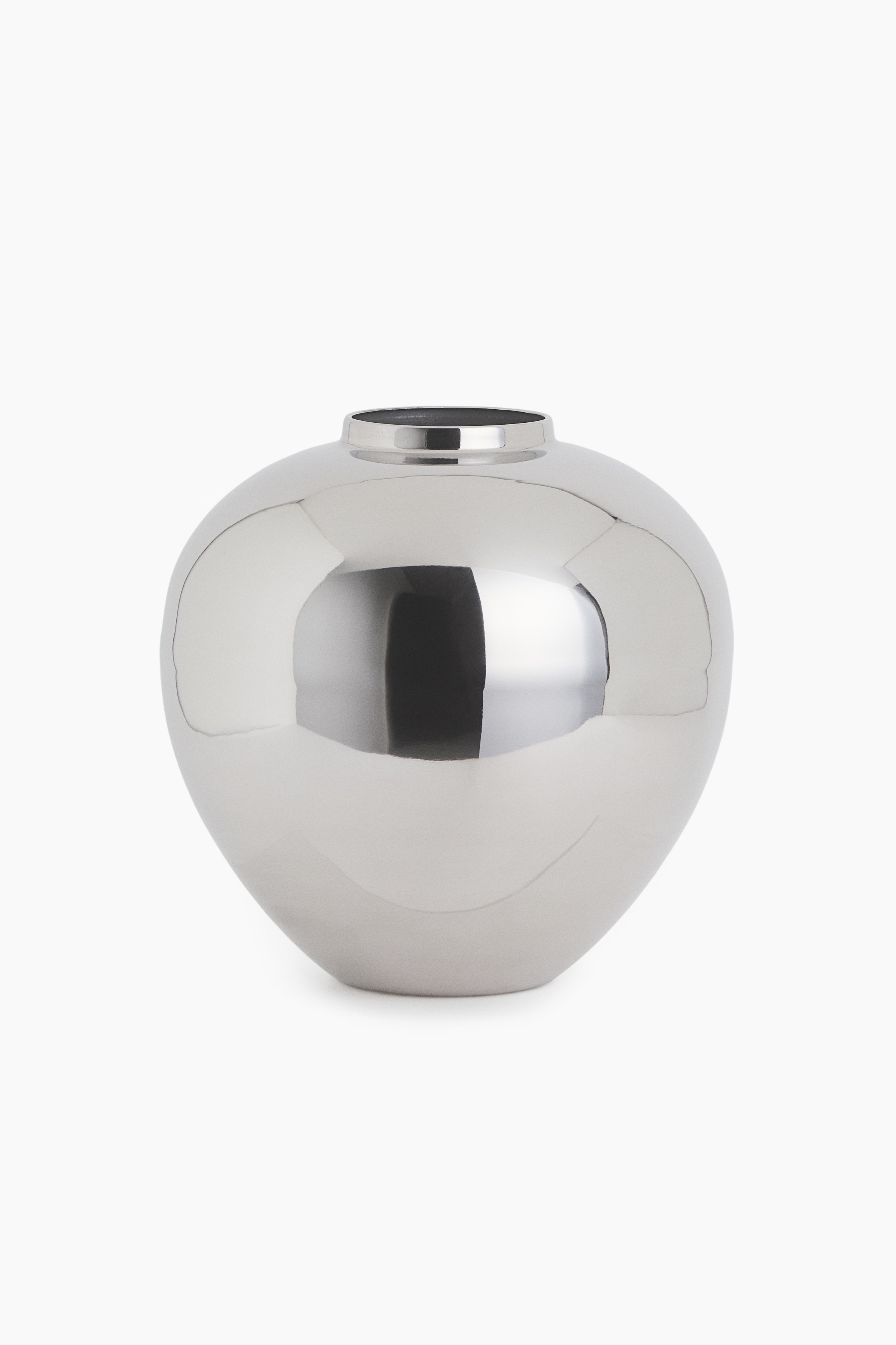 A stainless steel vase featuring a rounded design and a narrow mouth is facing front, holding a dense, cascading arrangement of textured white dried flora that is draping down its side.